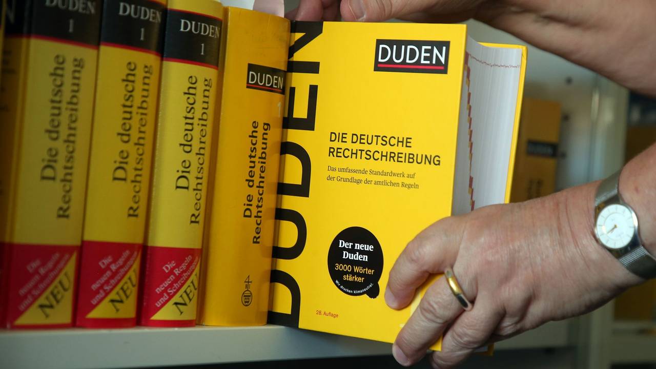 Der Duden wird aus einem Bücherregal gezogen.