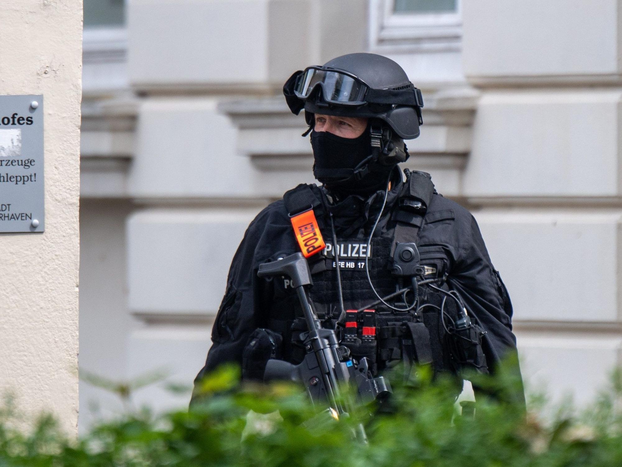 19.05.2022, Bremen, Bremerhaven: Eine Sondereinsatzkraft der Polizei ist vor der Schule im Einsatz. An einem Gymnasium in Bremerhaven ist am Donnerstagvormittag geschossen worden. Eine Frau sei mit der Waffe verletzt worden, sagte eine Polizeisprecherin. Der Täter wurde nach der Tat festgenommen. Foto: Sina Schuldt/dpa +++ dpa-Bildfunk +++