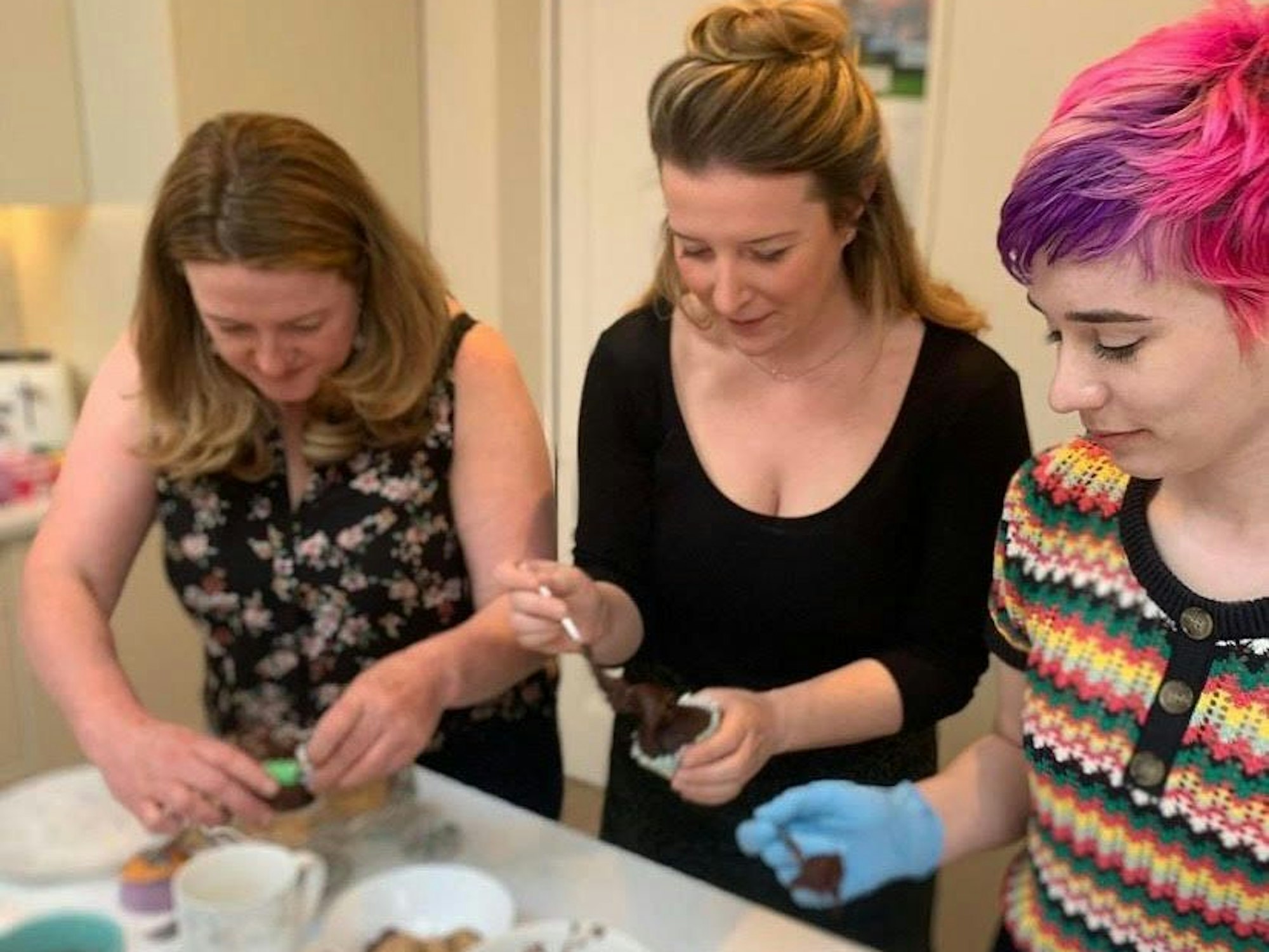 Drei Frauen stehen am Tisch und backen gemeinsam für Consider it Cakes.