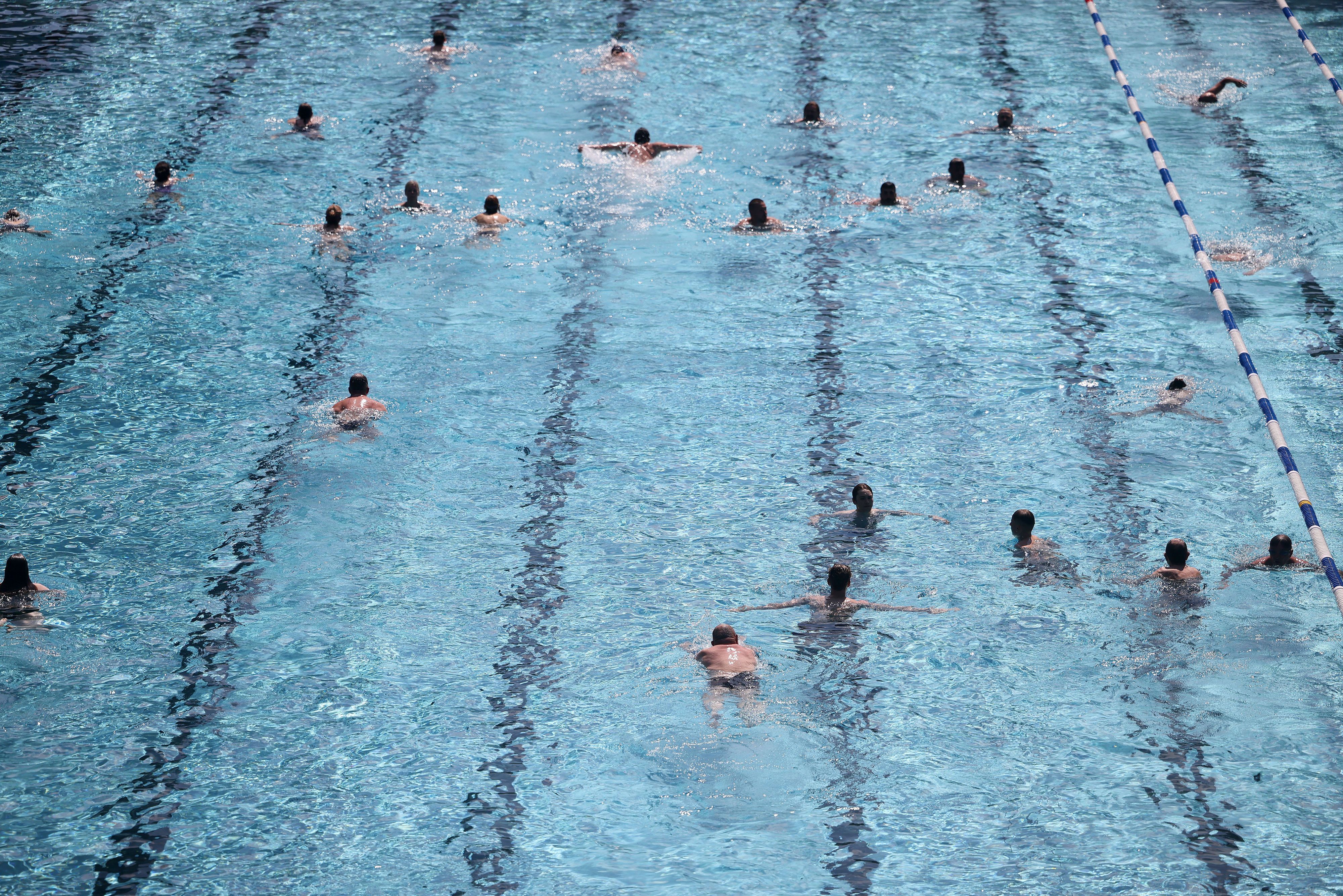 Menschen schwimmen in einem Freibad im Becken. Dürfen Frauen bald auch in Köln oben-ohne-baden?