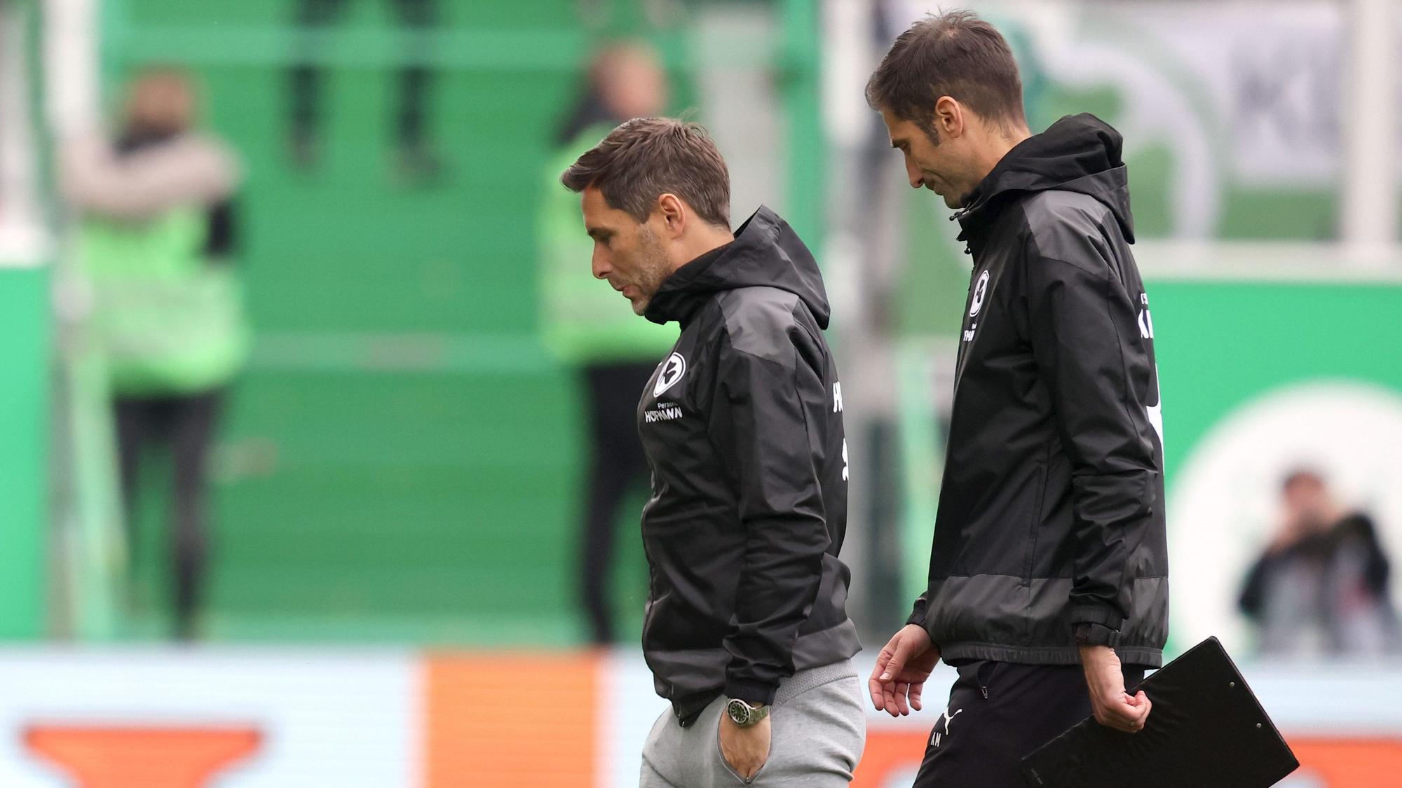 Stefan Leitl (l.) und Co-Trainer André Mijatovic gehen nach dem Bundesliga-Abstieg von Greuther Fürth vom Rasen. Der Start bei Hannover 96 in der 2. Bundesliga könnte sich für das Duo verzögern.