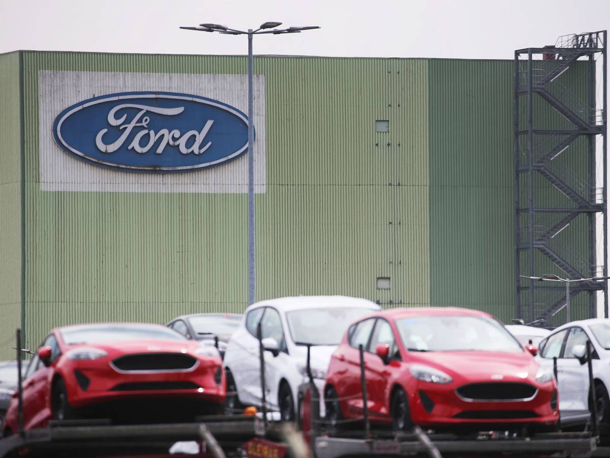 Neu gebaute Autos stehen auf Lastwagen vor dem Ford Werk.