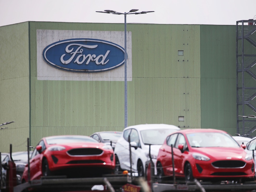 Neu gebaute Autos stehen auf Lastwagen vor dem Ford Werk.