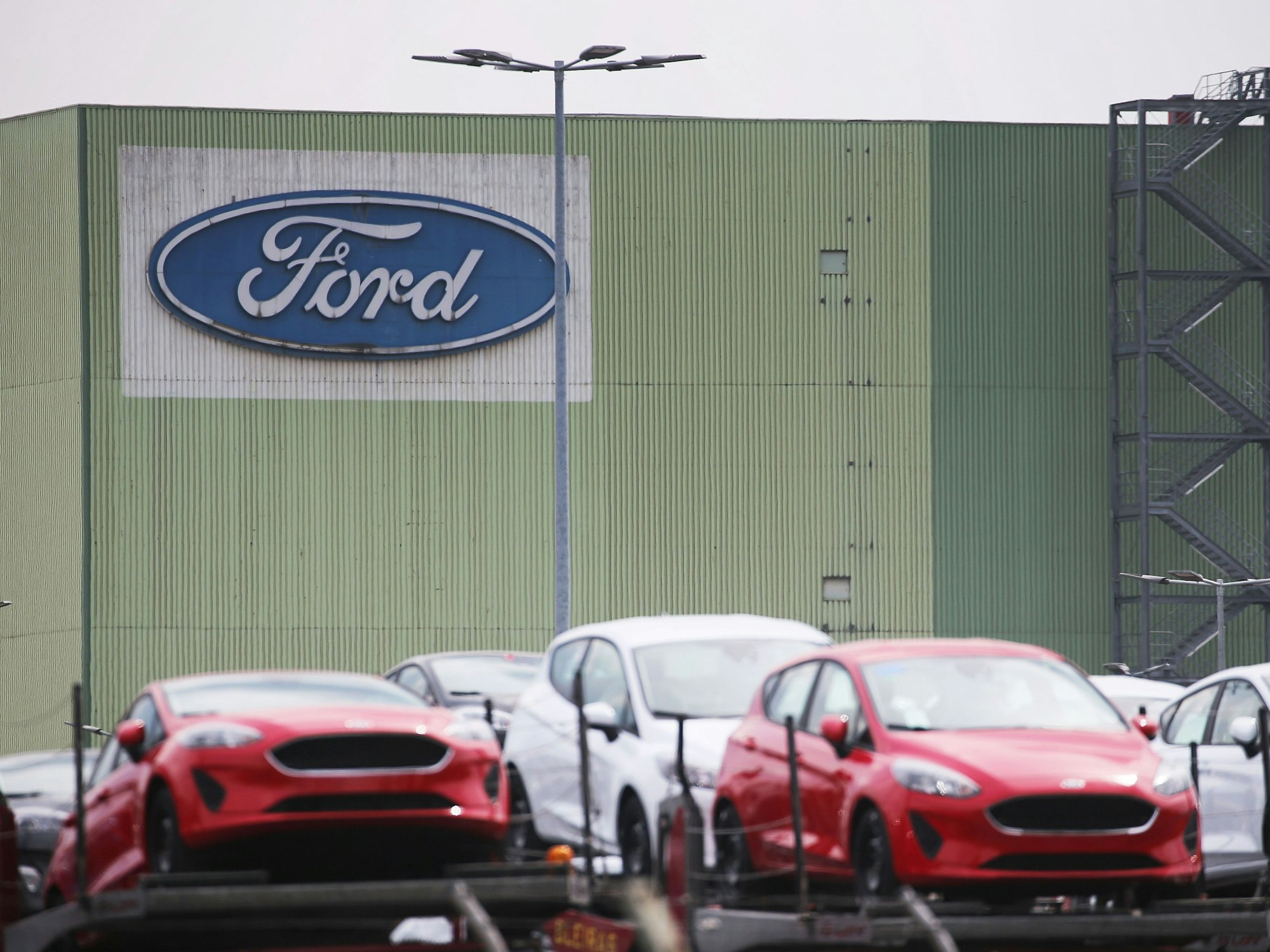 Neu gebaute Autos stehen auf Lastwagen vor dem Ford Werk.