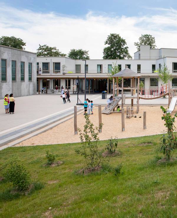 Auf dem Spielplatz vor der Friedrich-List-Schule in Köln-Porz spielen und klettern Kinder.
