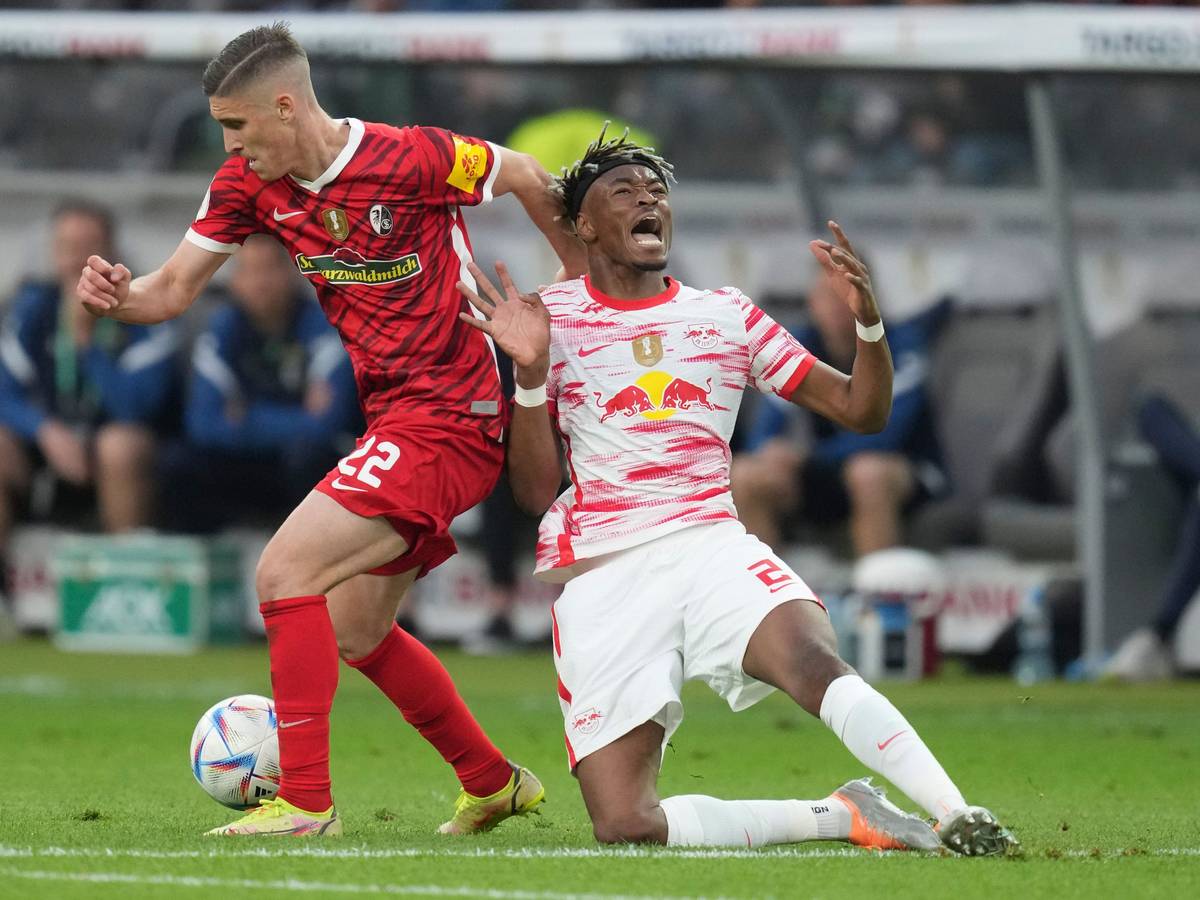 Freiburg's Roland Sallai, left, and Leipzig's Mohamed Simakan fight for the ball during the German Soccer Cup final match between SC Freiburg and RB Leipzig at the Olympic Stadium in Berlin, Germany, Saturday, May 21, 2022. (AP Photo/Michael Sohn)