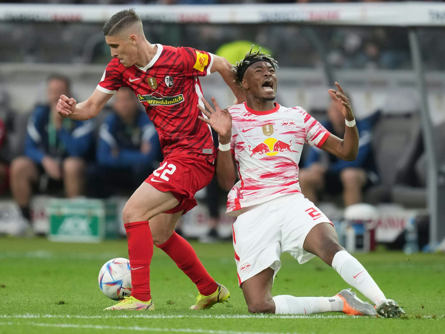 Freiburg's Roland Sallai, left, and Leipzig's Mohamed Simakan fight for the ball during the German Soccer Cup final match between SC Freiburg and RB Leipzig at the Olympic Stadium in Berlin, Germany, Saturday, May 21, 2022. (AP Photo/Michael Sohn)