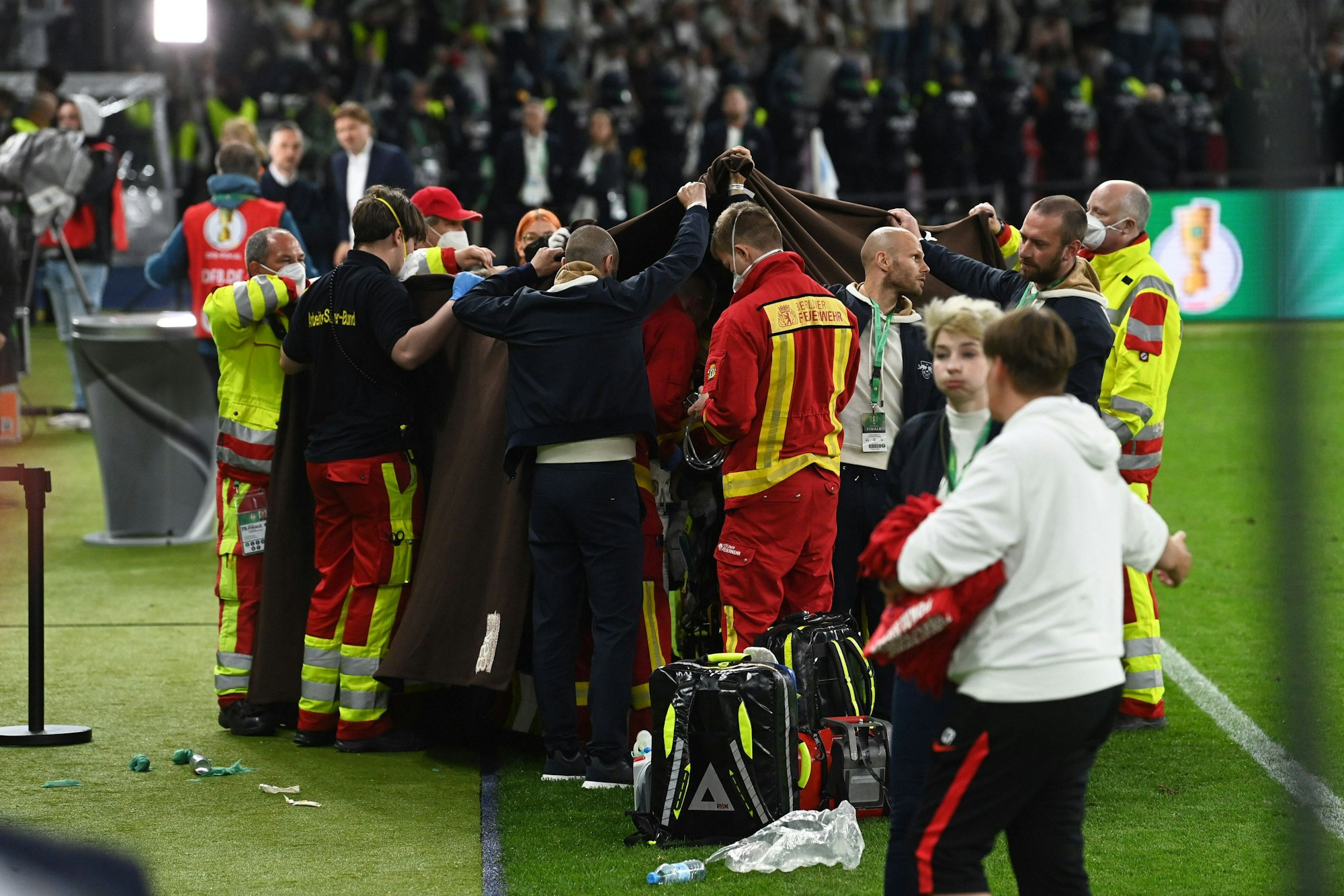 Medizinische Angestellte schirmen den Mann ab, der beim DFB-Pokal-Finale eine Herzattacke erlitten hatte