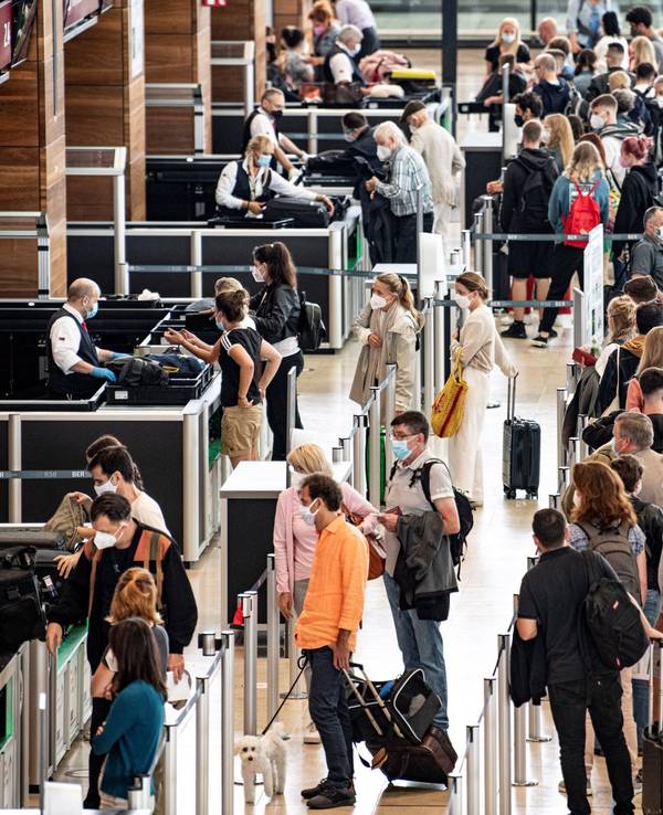 Reisende stehen am Flughafen am Check-In-Schalter.