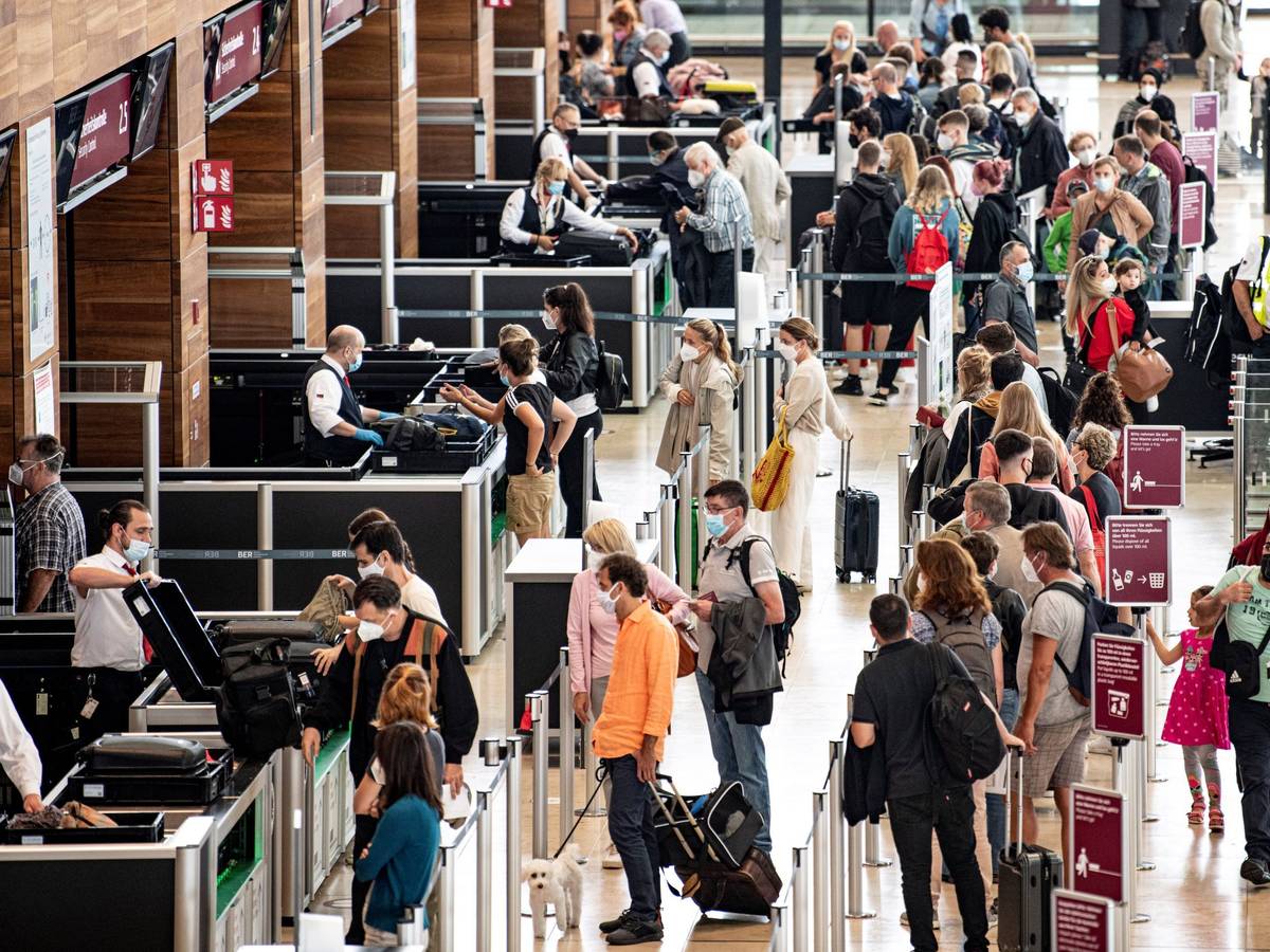 Reisende stehen am Flughafen am Check-In-Schalter.