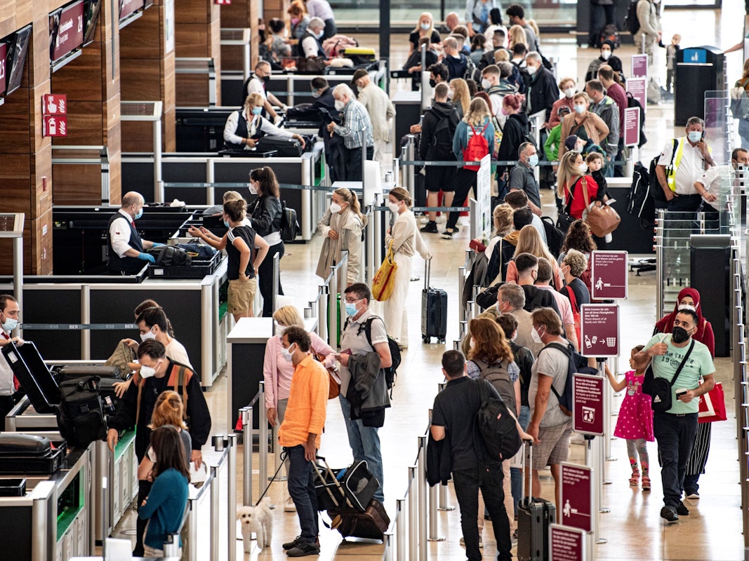 Reisende stehen am Flughafen am Check-In-Schalter.