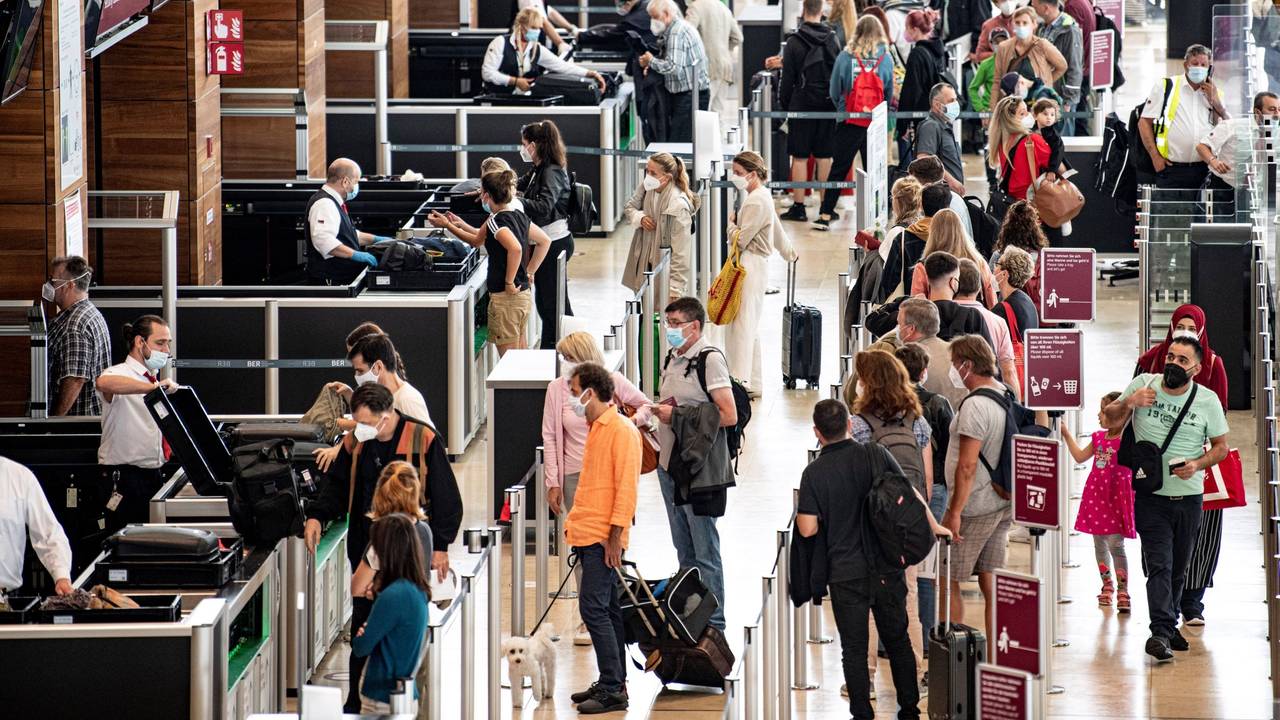 Reisende stehen am Flughafen am Check-In-Schalter.