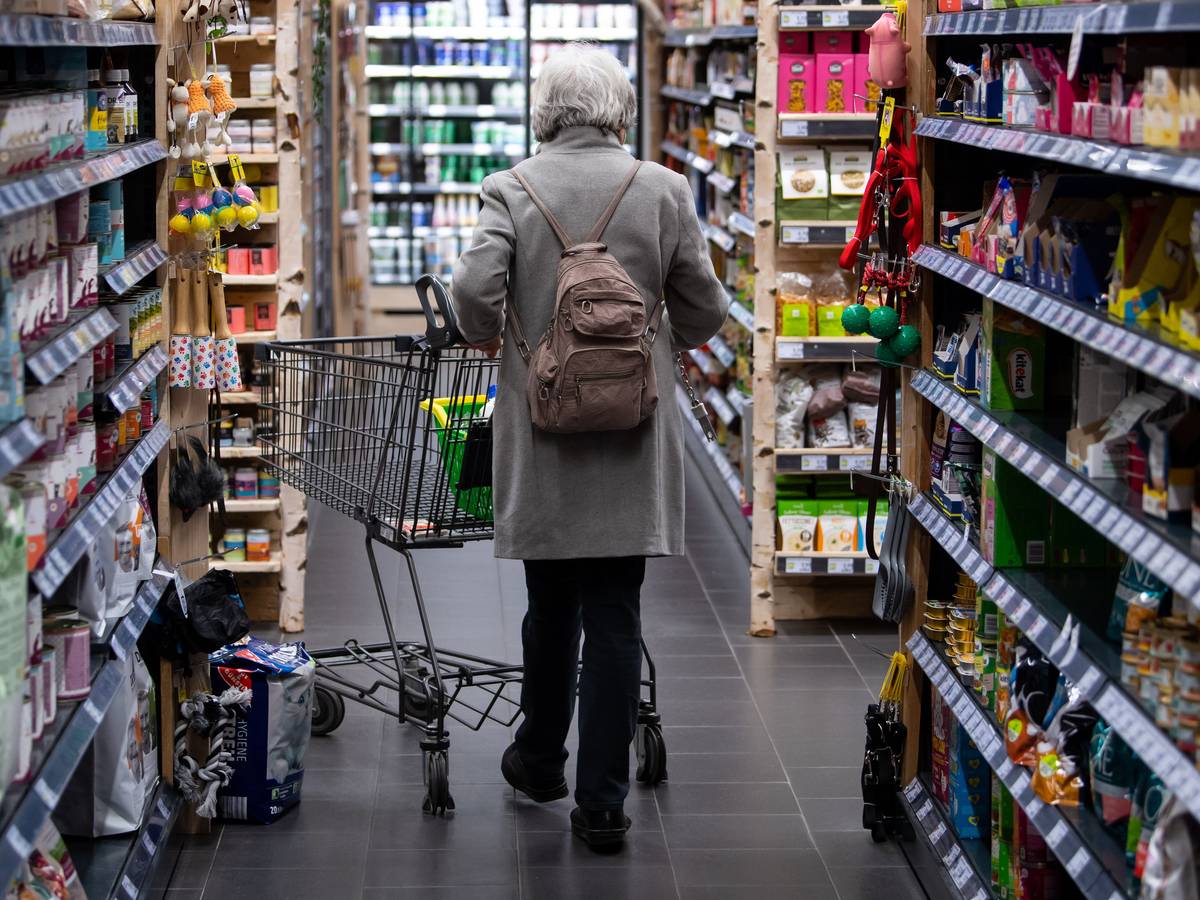 Eine Frau geht mit ihrem Einkaufswagen durch einen Supermarkt. Die hohen Preise von Lebensmitteln zwingen viele Menschen dazu, ihr Einkaufsverhalten zu ändern.