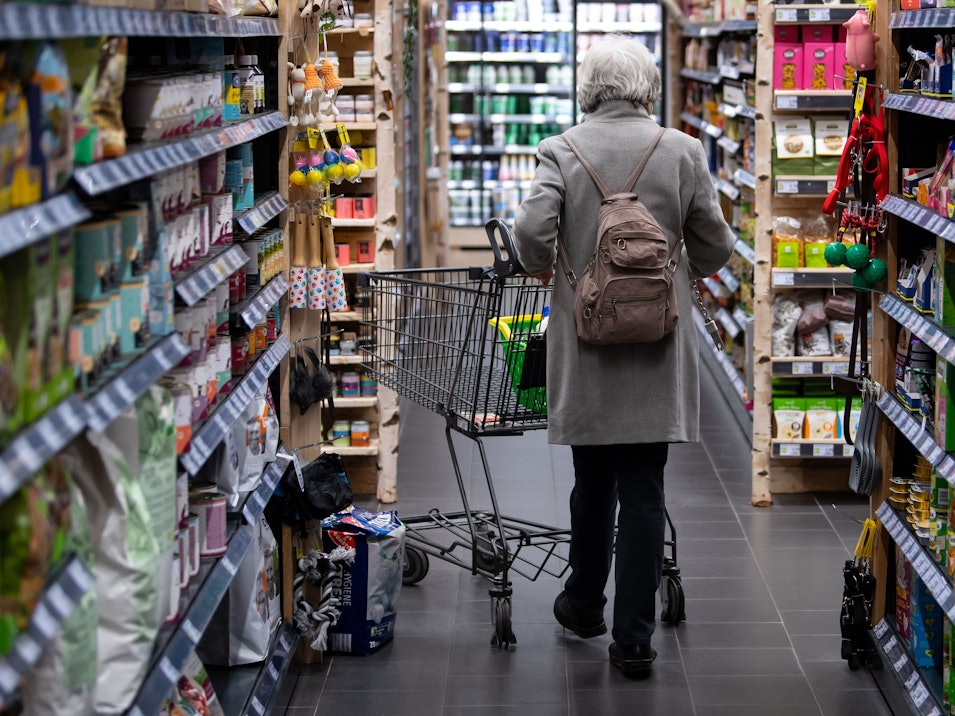 Eine Frau geht mit ihrem Einkaufswagen durch einen Supermarkt. Die hohen Preise von Lebensmitteln zwingen viele Menschen dazu, ihr Einkaufsverhalten zu ändern.