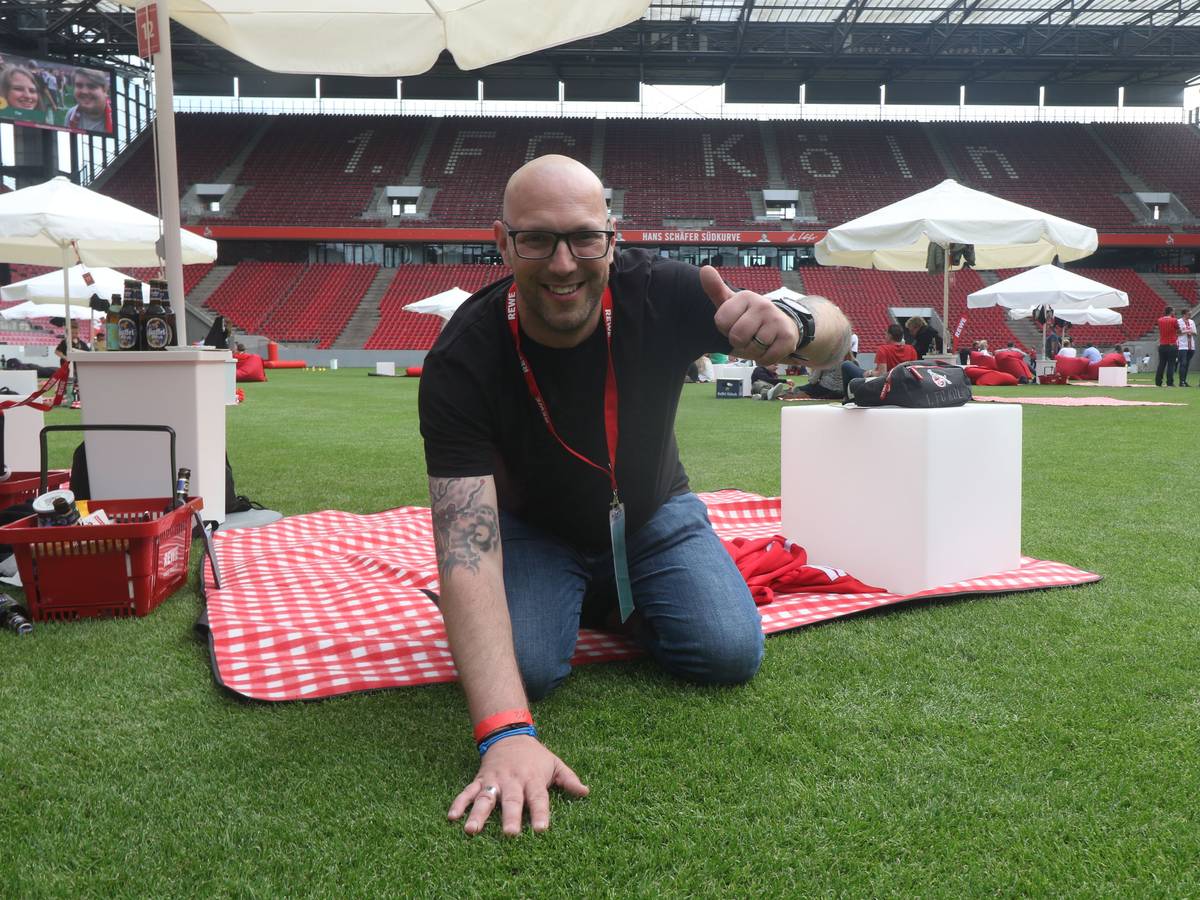 Ein Mann kniet auf dem Rasen in einem Fußballstadion.