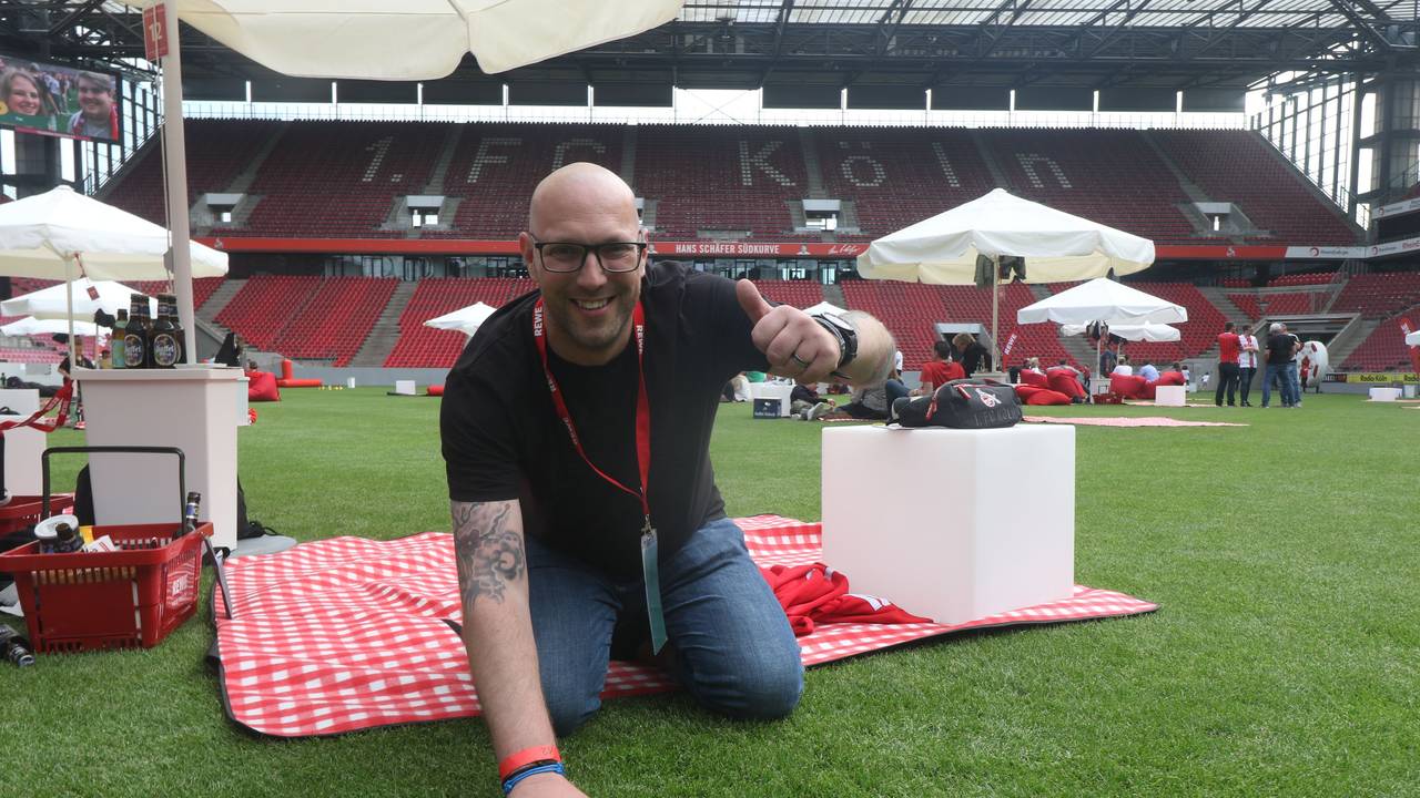 Ein Mann kniet auf dem Rasen in einem Fußballstadion.