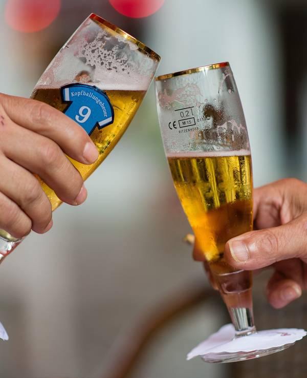 Zwei Personen stoßen mit ihren Biergläsern an.