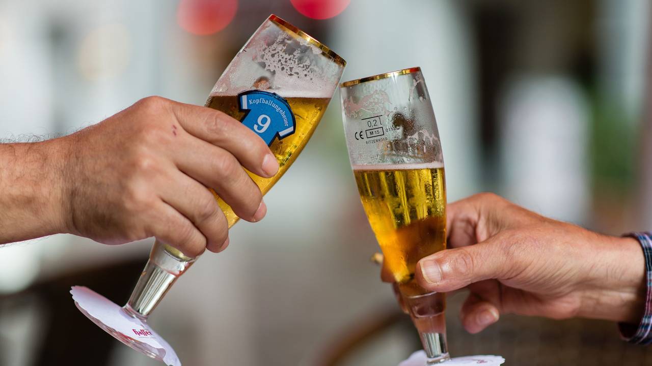 Zwei Personen stoßen mit ihren Biergläsern an.