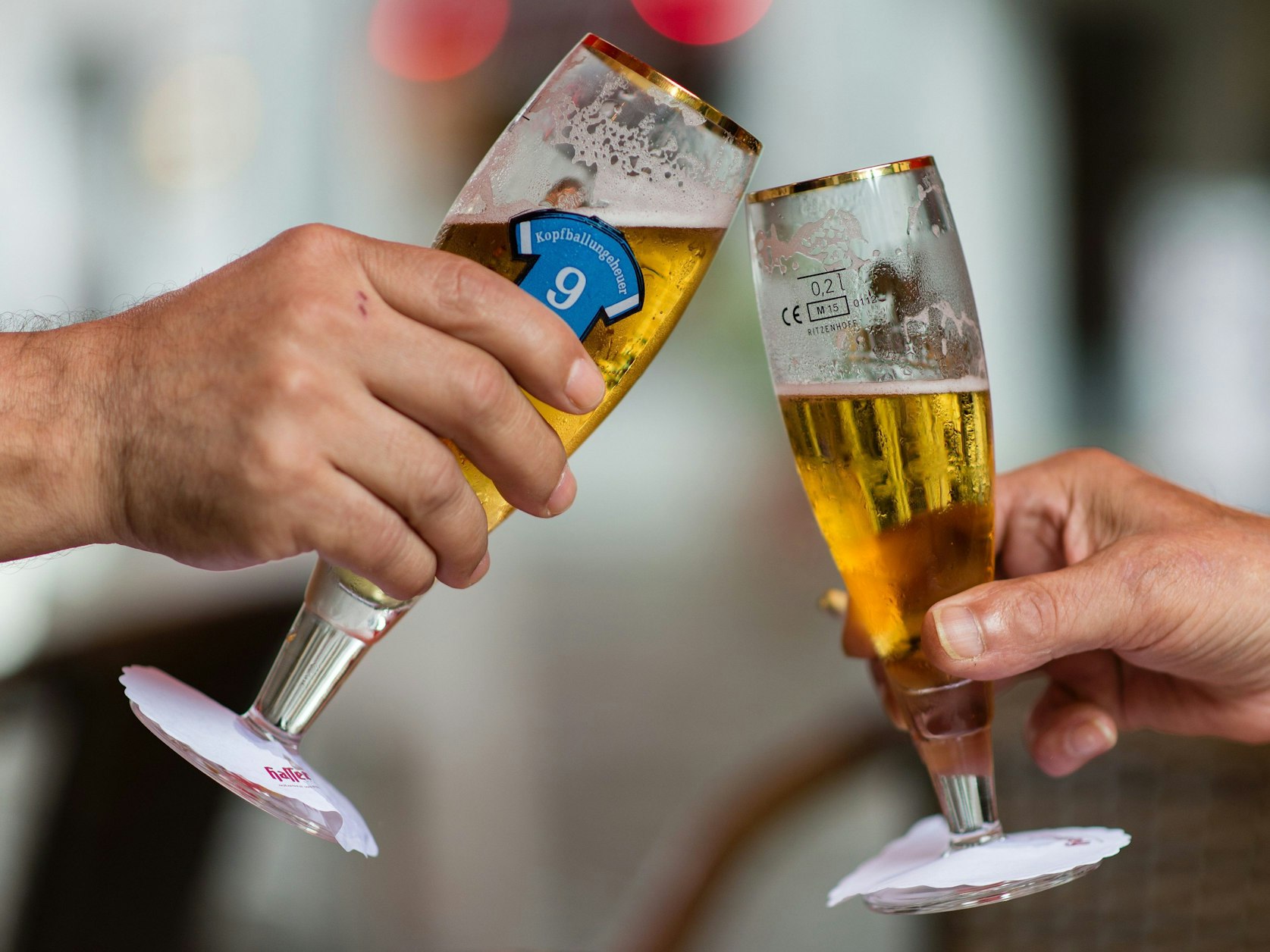 Zwei Personen stoßen mit ihren Biergläsern an.