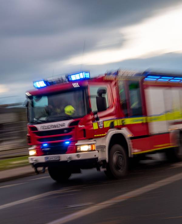Ein Fahrzeug der Feuerwehr fährt mit Blaulicht über eine Straße.