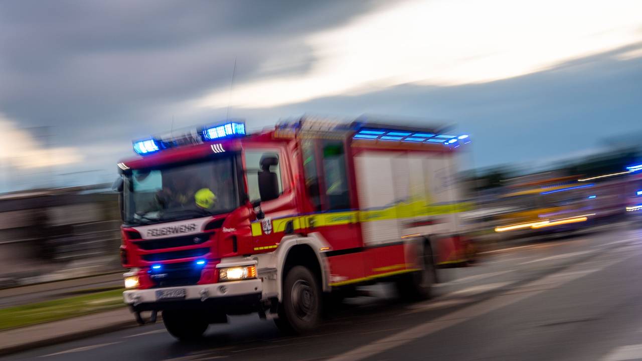 Ein Fahrzeug der Feuerwehr fährt mit Blaulicht über eine Straße.
