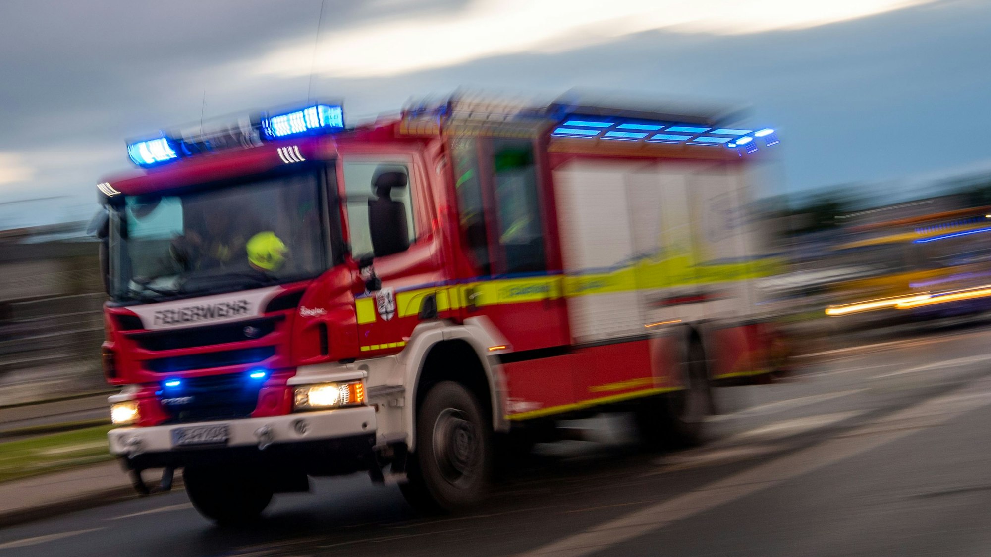Ein Fahrzeug der Feuerwehr fährt mit Blaulicht über eine Straße.