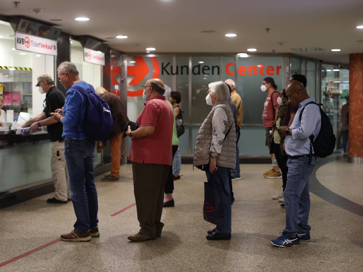 Menschen stehen Schlange an einem Schalter für Fahrkarten.