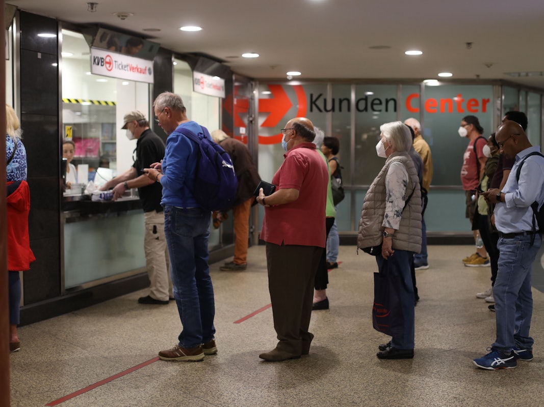 Menschen stehen Schlange an einem Schalter für Fahrkarten.