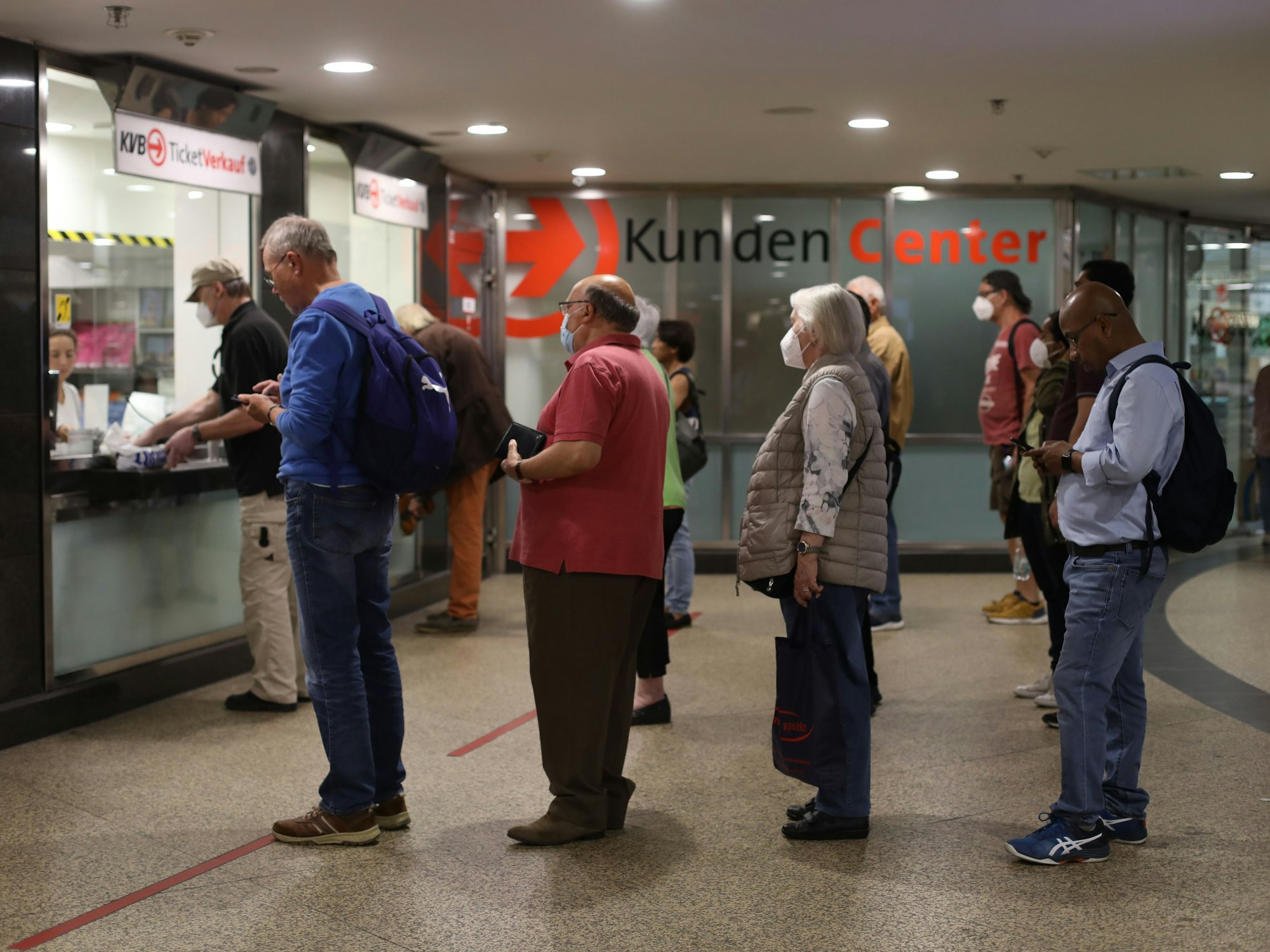 Menschen stehen Schlange an einem Schalter für Fahrkarten.