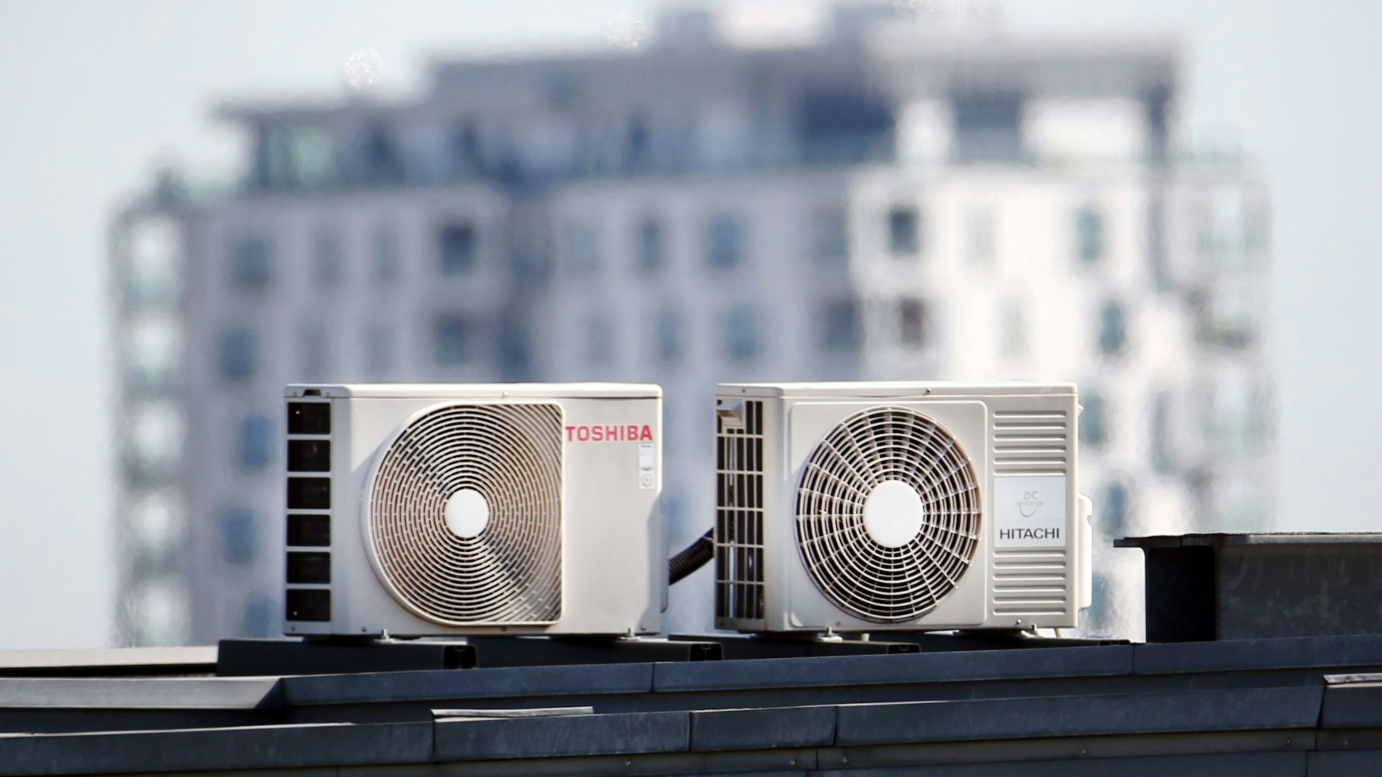 Zwei Klimageräte stehen auf einem Dach.