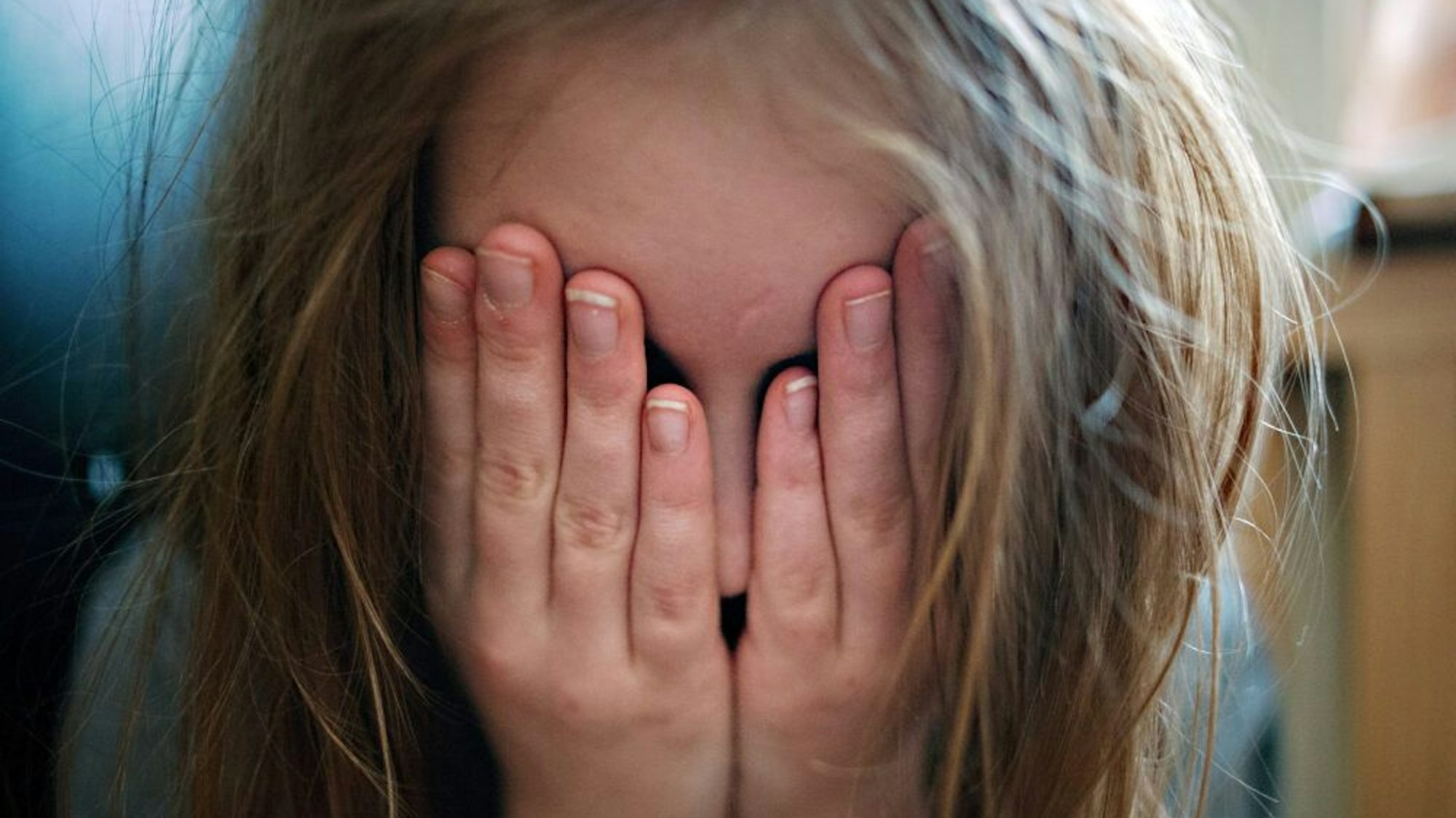 Ein Mädchen hält sich die Hände vor das Gesicht.