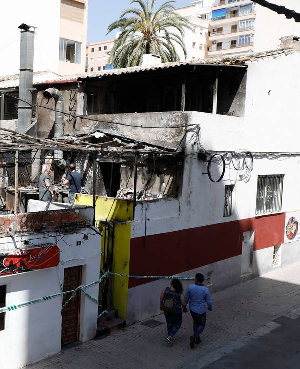 Menschen gehen nach einem Brand am Restaurant «Why Not Mallorca?» vorbei. Die Polizei hat auf Mallorca 13 deutsche Urlauber festgenommen, weil sie den Brand ausgelöst haben sollen.