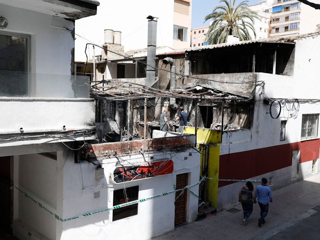 Menschen gehen nach einem Brand am Restaurant «Why Not Mallorca?» vorbei. Die Polizei hat auf Mallorca 13 deutsche Urlauber festgenommen, weil sie den Brand ausgelöst haben sollen.