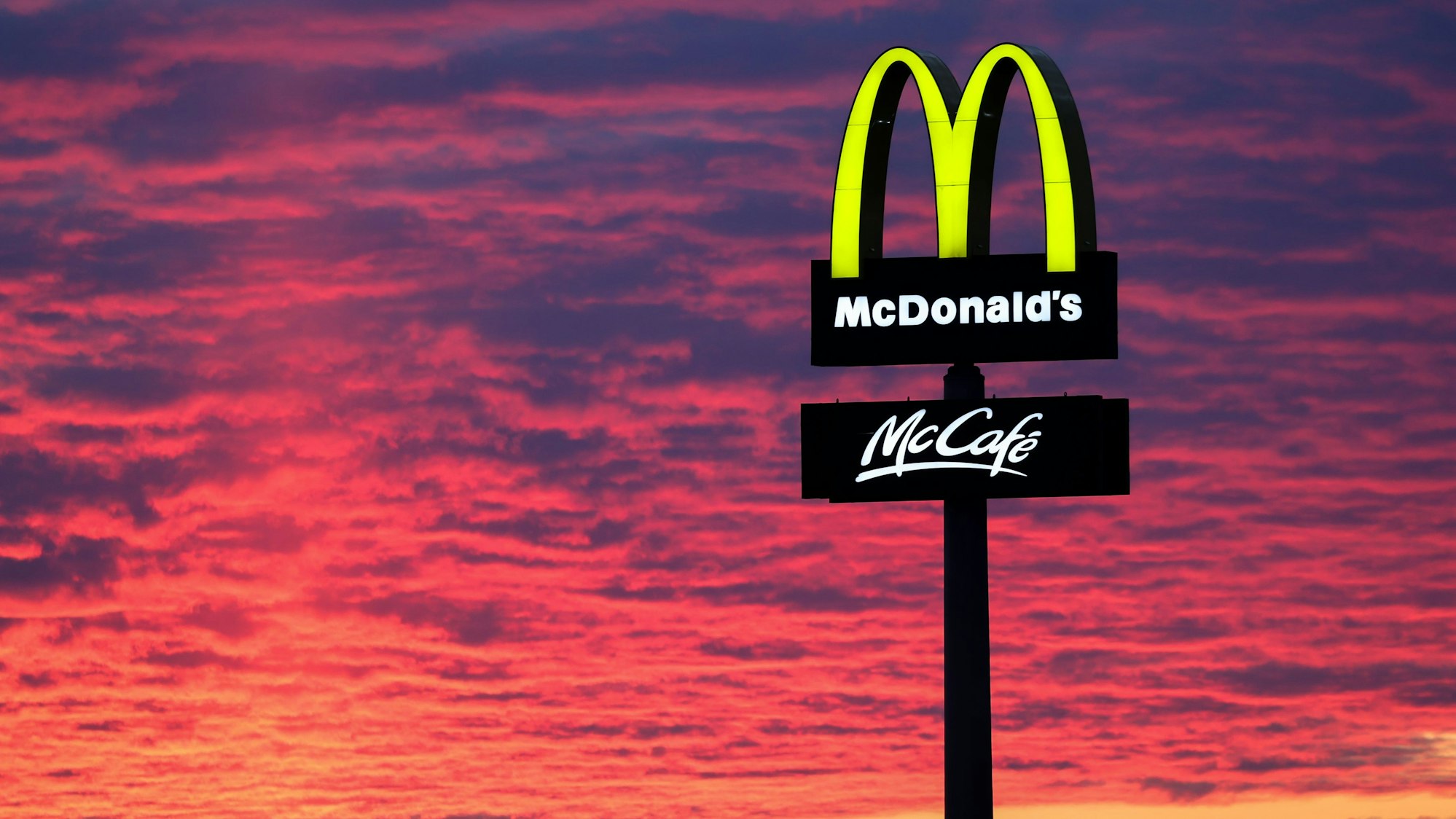 Der Abendhimmel leuchtet rötlich am 30. November 2020 hinter einem McDonalds-Logo.