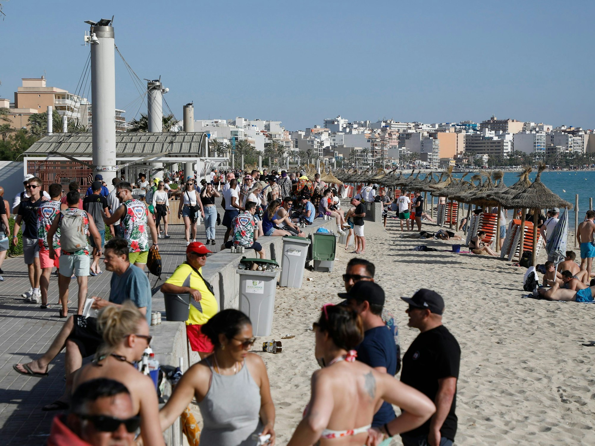 Menschen halten sich am Strand von Arenal in der Abenddämmerung auf.