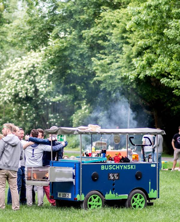 Eine Gruppe junger Männer feiert bei einer Vatertagstour mit einem umgebauten Bollerwagen.
