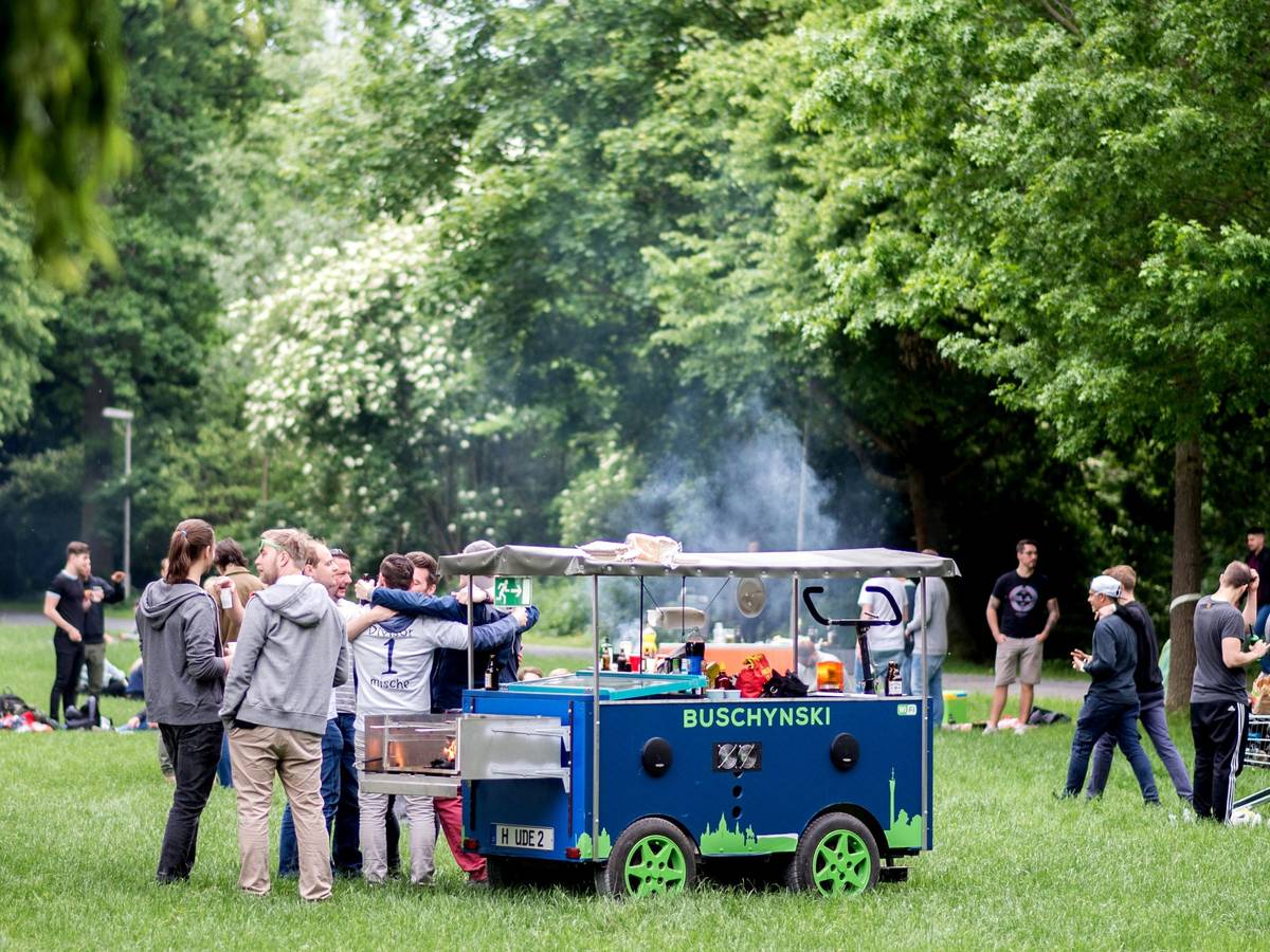 Eine Gruppe junger Männer feiert bei einer Vatertagstour mit einem umgebauten Bollerwagen.