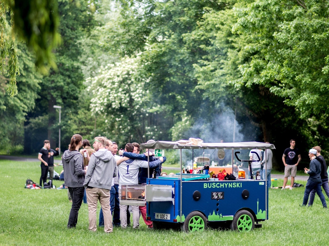 Eine Gruppe junger Männer feiert bei einer Vatertagstour mit einem umgebauten Bollerwagen.