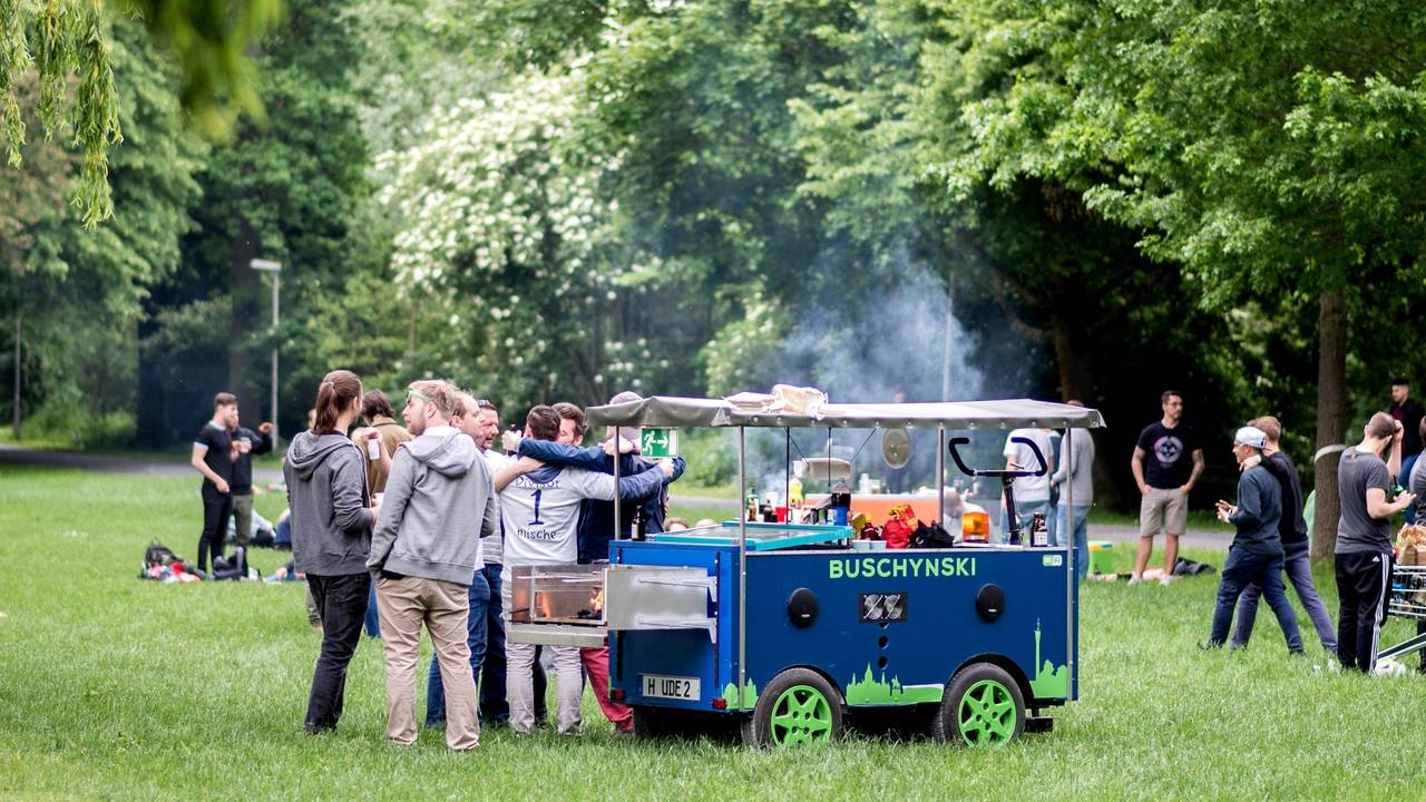 Eine Gruppe junger Männer feiert bei einer Vatertagstour mit einem umgebauten Bollerwagen.