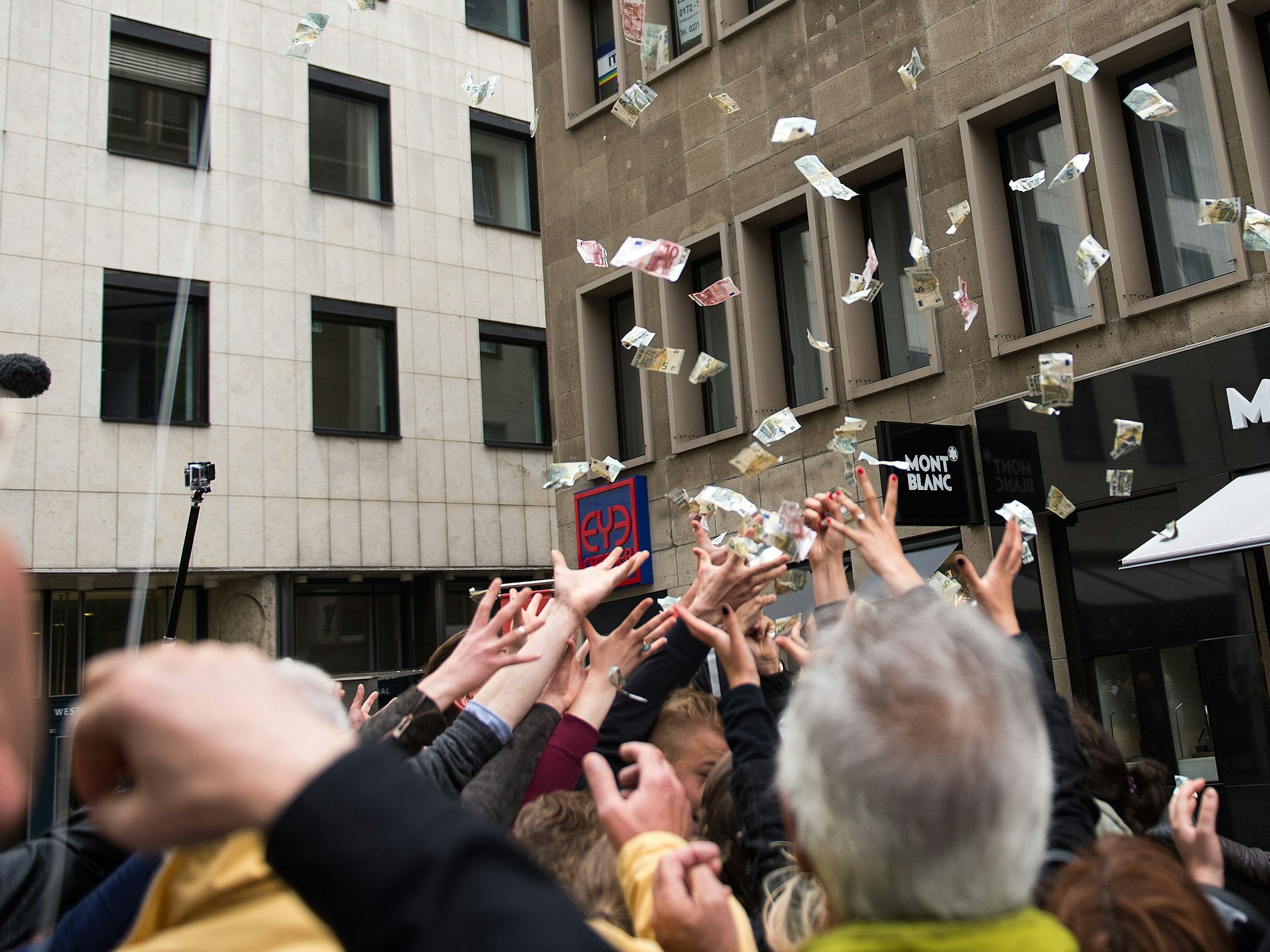 Passanten versuchen am 19. Juni 2015 in Köln (Nordrhein-Westfalen) wehende Geldscheine zu greifen.