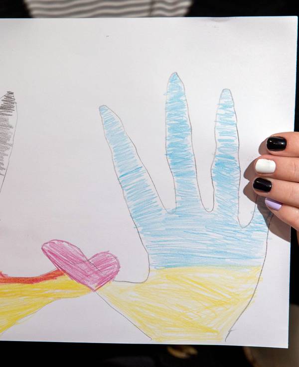Zwei von Kindern gemalte Hände, eine in deutschen und eine in ukrainischen Farben, formen mit ihren Daumen ein rosa Herz.