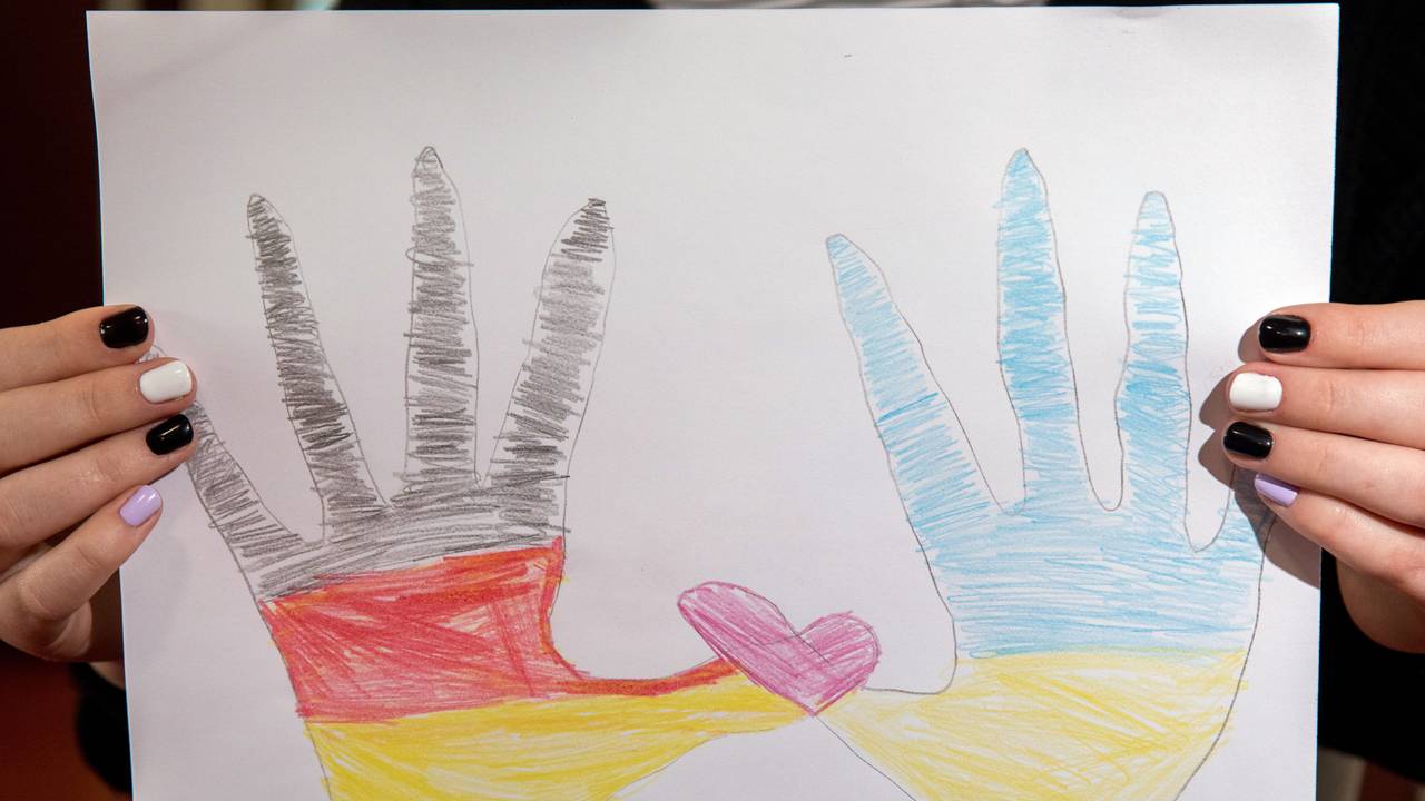 Zwei von Kindern gemalte Hände, eine in deutschen und eine in ukrainischen Farben, formen mit ihren Daumen ein rosa Herz.