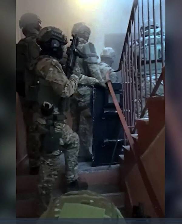 Vermummte Spezialkräfte stehen in einem Treppenhaus vor einer Wohnung, die sie gleich stürmen.