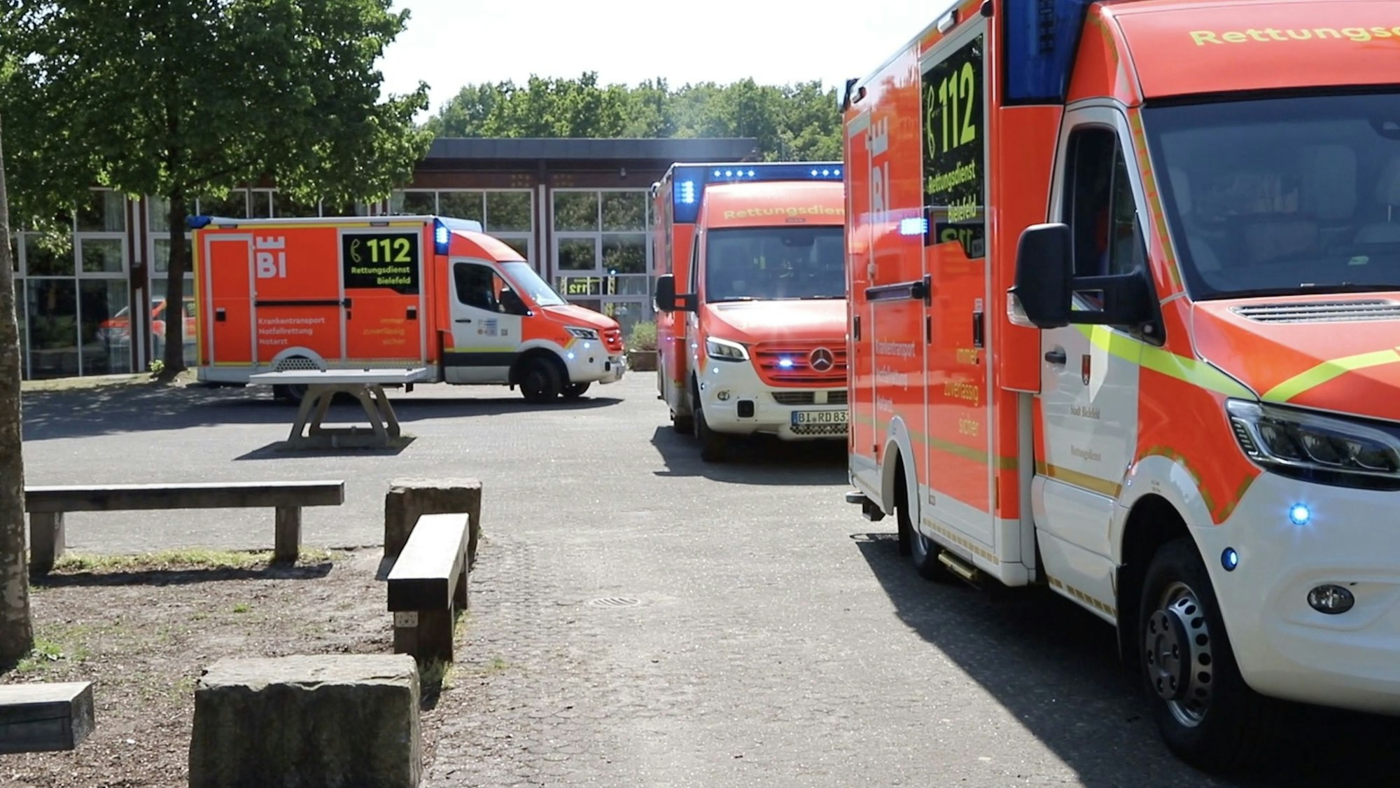 Einsatzfahrzeuge vom Rettungsdienst stehen vor einer Schule.