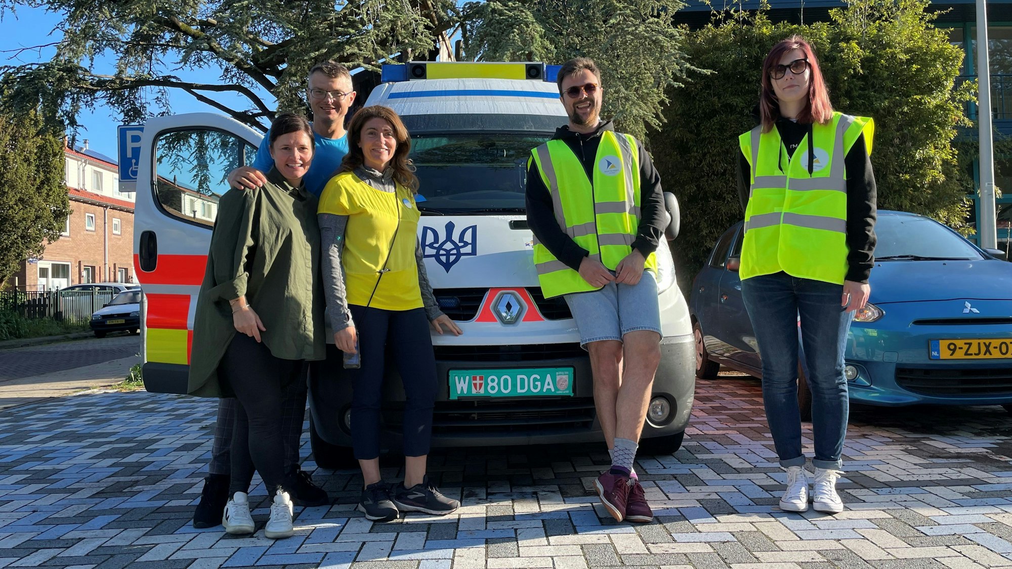 Natalie, Sascha und Linda vom „Blau-Gelben Kreuz“ aus Köln stehen vor einem Krankenwagen, außerdem Fahrer Dimitro sowie Veronika von der holländischen Organisation „Zeilen van Vrijheid“.