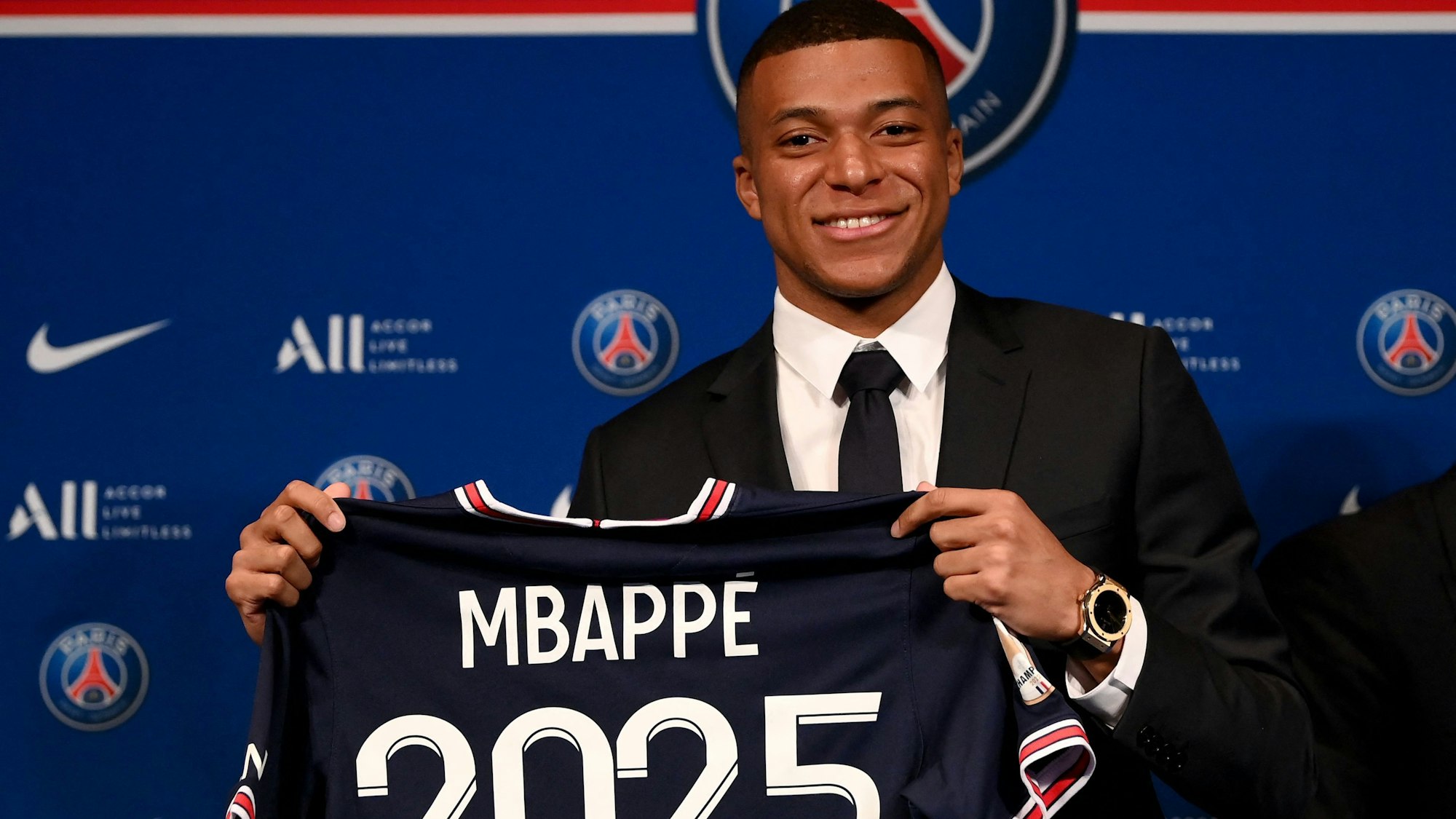Kylian Mbappé hält bei der Verkündung seiner Vertragsverlängerung bis 2025 bei Paris Saint-Germain ein Trikot mit seinem Namen und der Zahl 2025 hoch