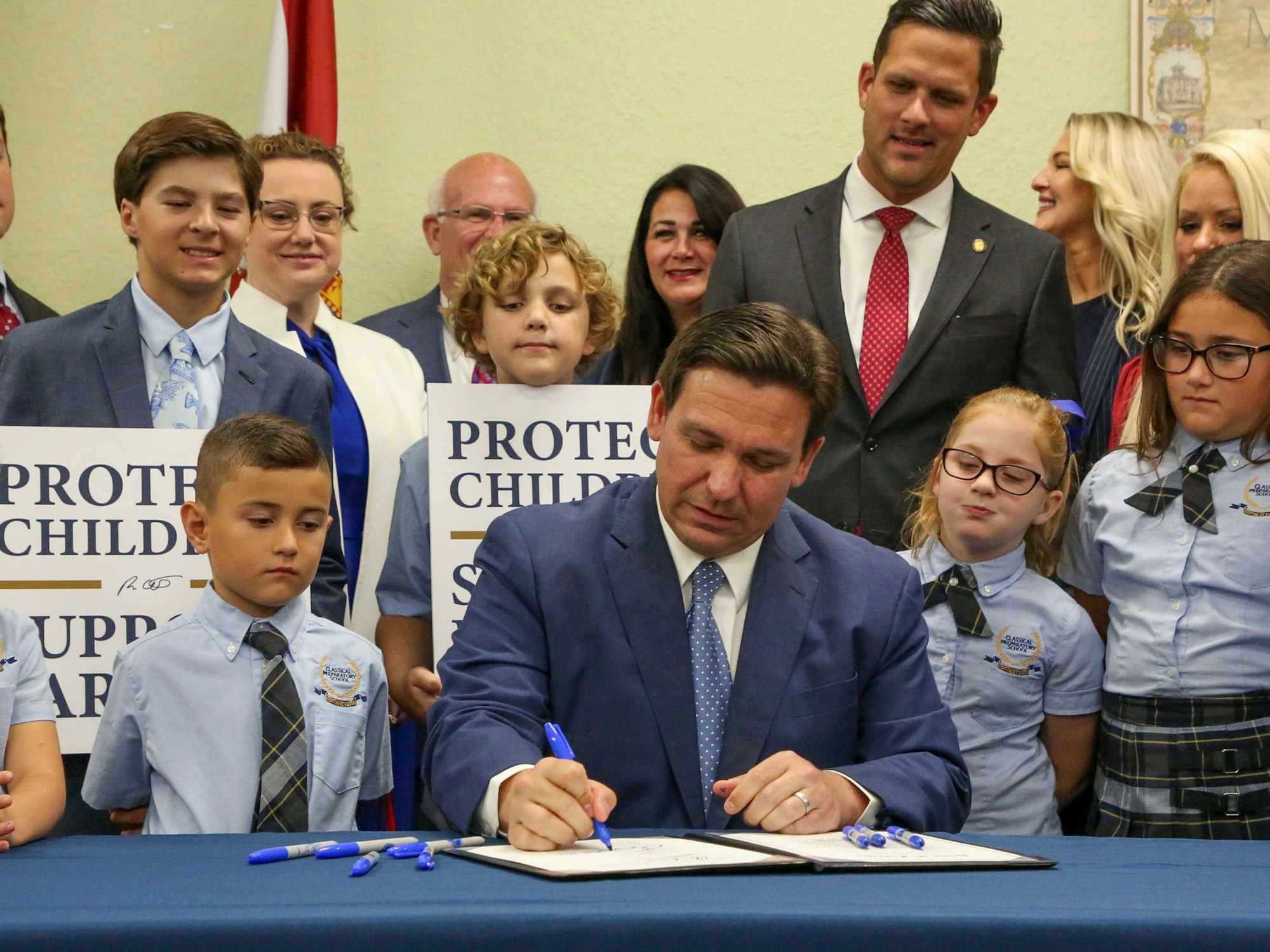 Gouverneur Ron DeSantis unterzeichnet ein Gesetz in Florida. Um ihn stehen mehrere Schülerinnen und Schüler.