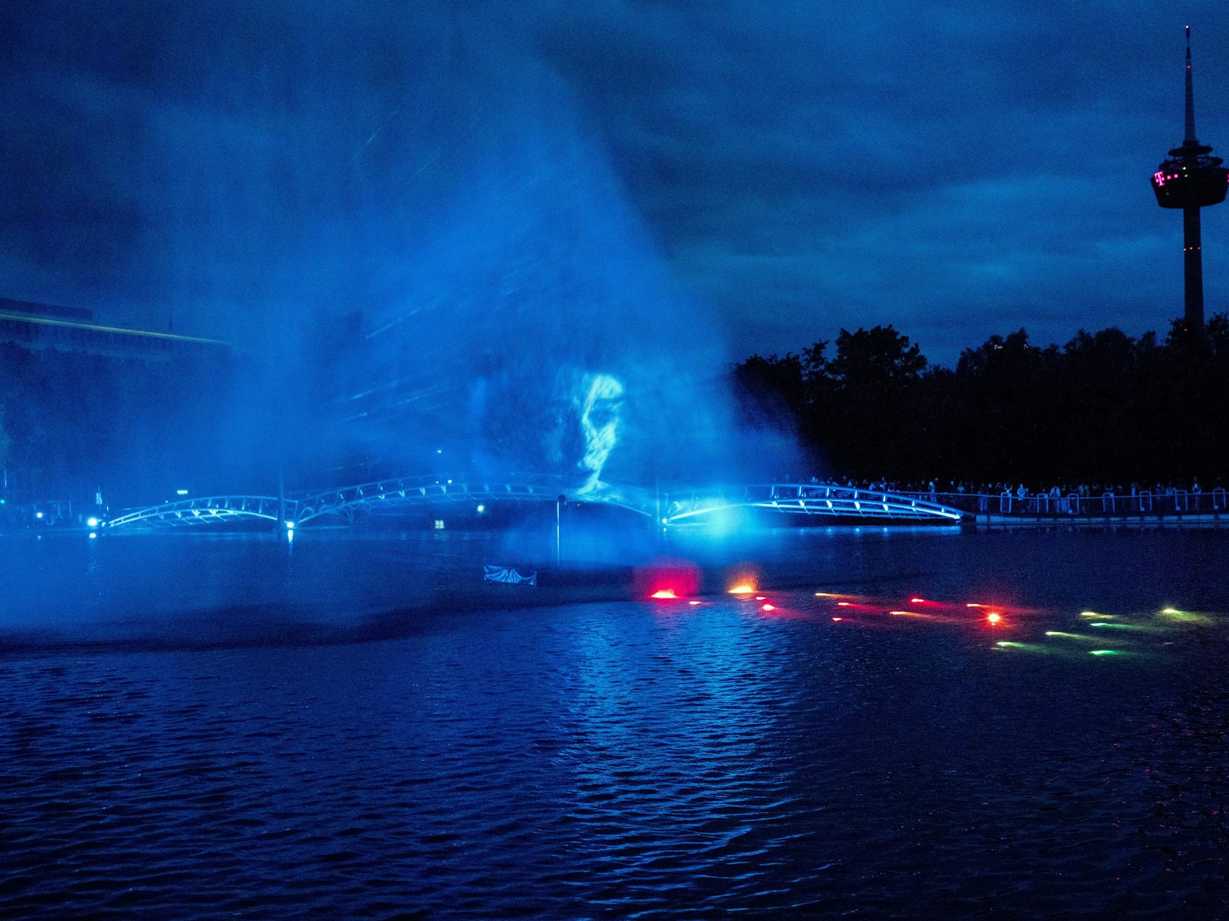 In der Lichtshow auf dem See im Kölner Mediapark wird das Gesicht einer Schauspielerin aus der Serie Stranger Things auf Wassernebel projiziert.