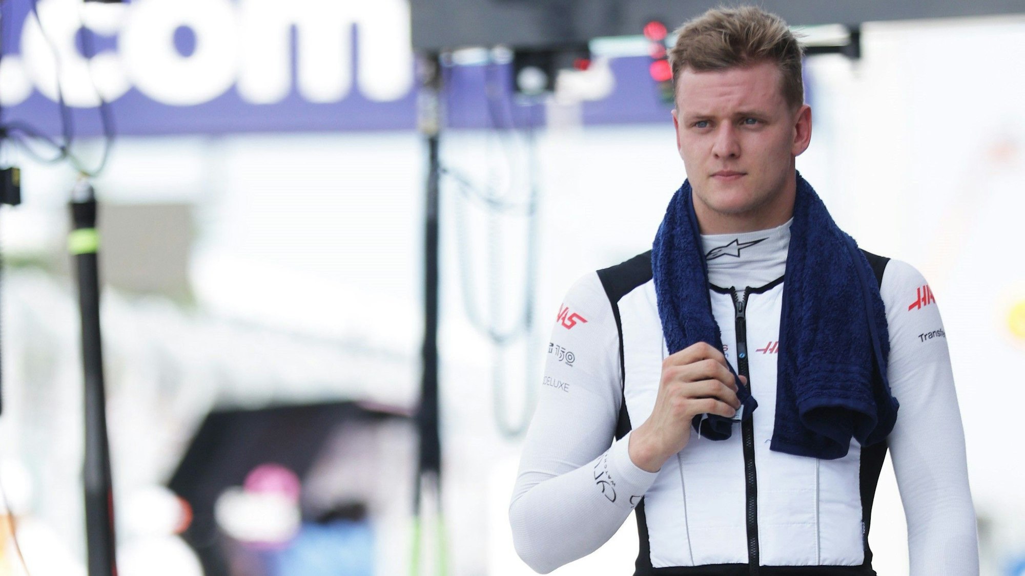 Mick Schumacher geht mit einem Handtuch über den Schultern durch die Boxengasse der Formel 1