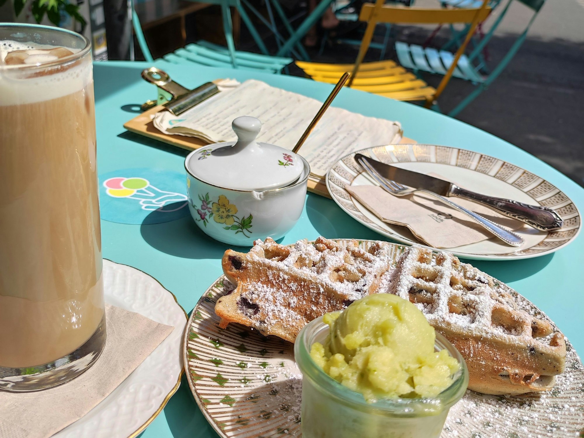 Eine Heidelbeerwaffel, eine Kugel Pfirsich-Maracuja-Basilikum-Sorbet und ein Cold Brew in der Eisdielerin in Köln Ehrenfeld.